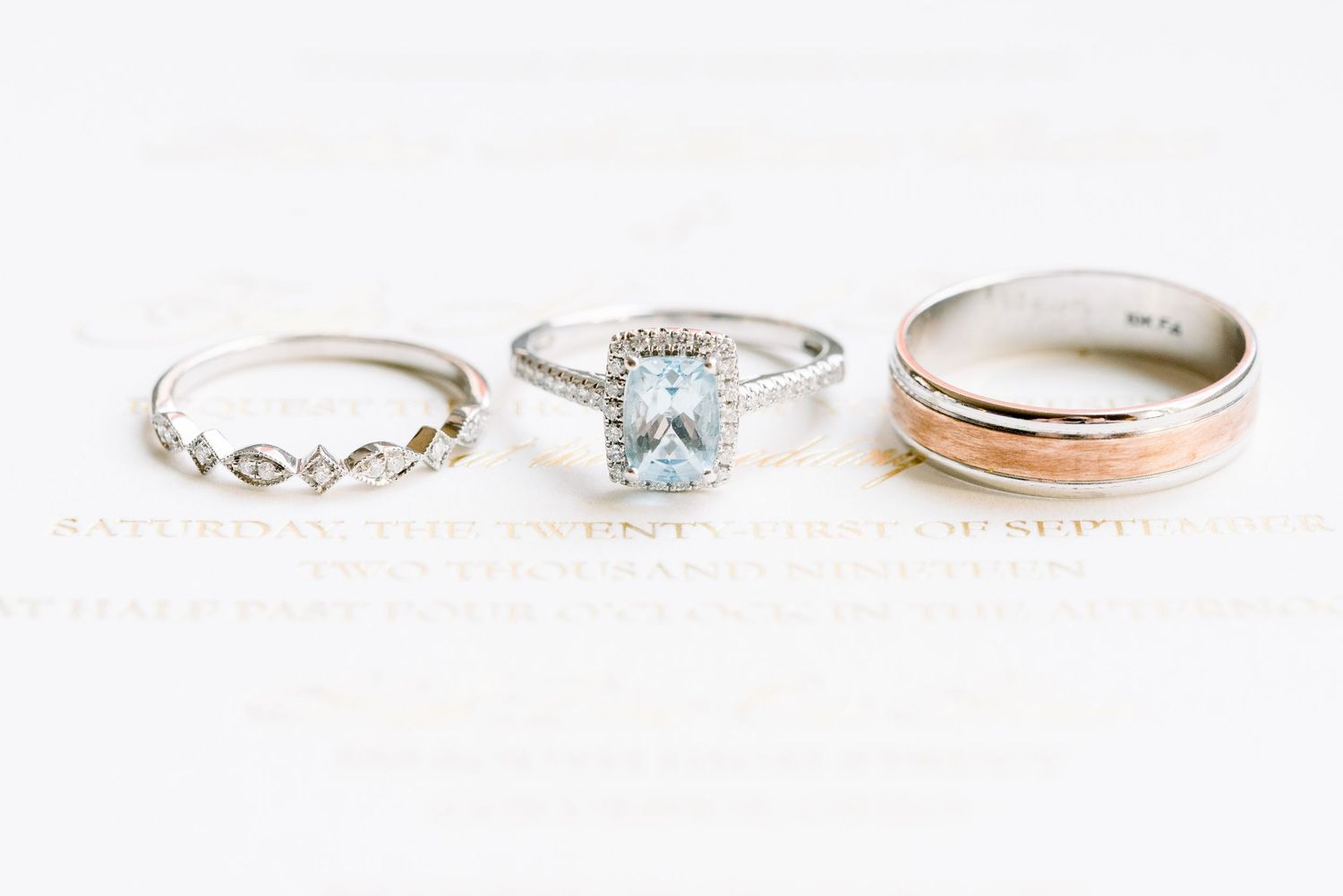 A collection of delicate engagement rings and wedding bands featuring diamonds and gemstones displayed on a white surface.