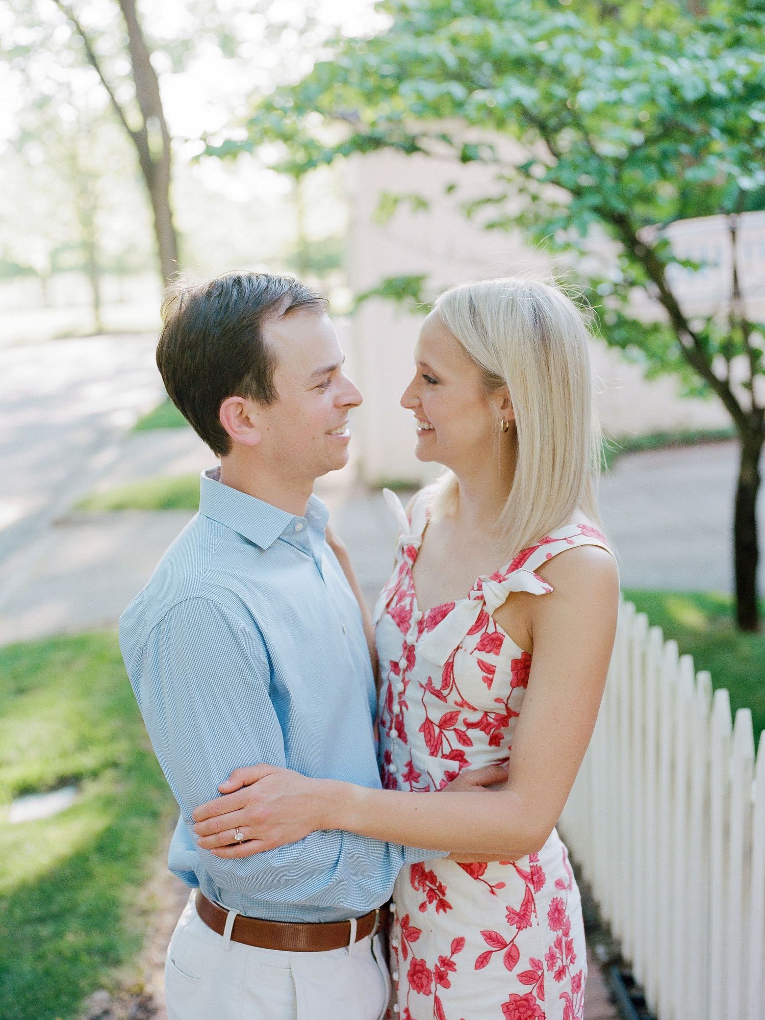 A couple shares tender moments in a garden setting wearing blue shirt and red floral dress.
