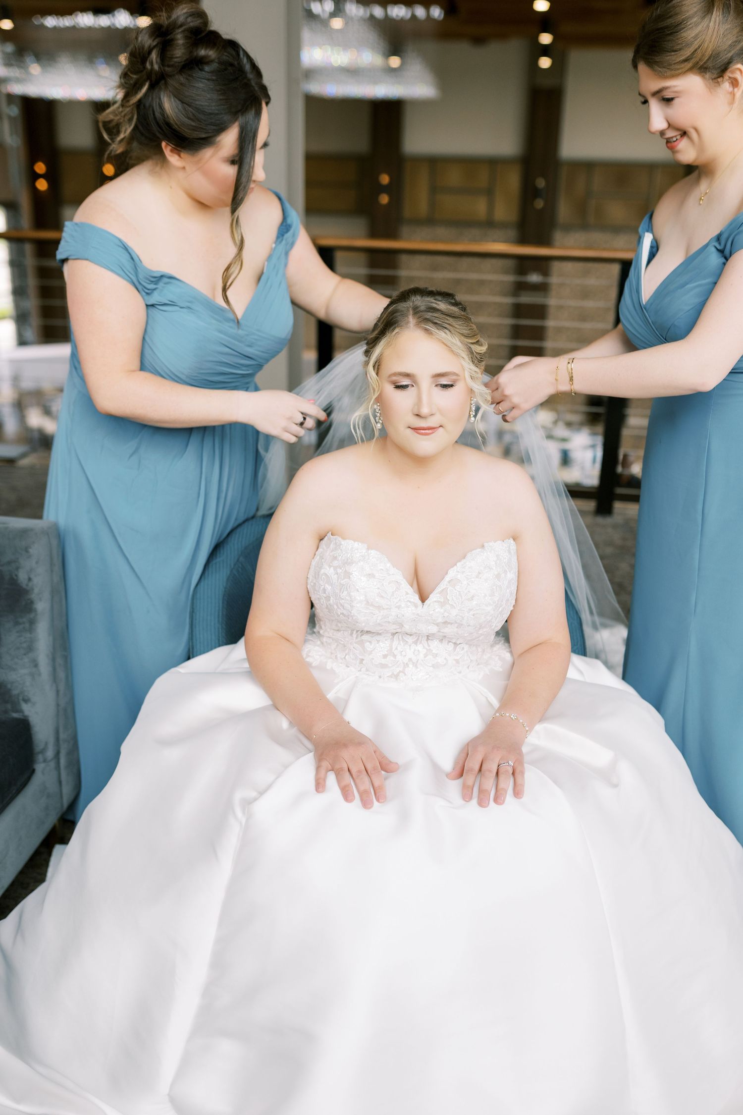 Bridesmaids in dusty blue dresses help adjust a white wedding gown in a series of candid preparation shots.