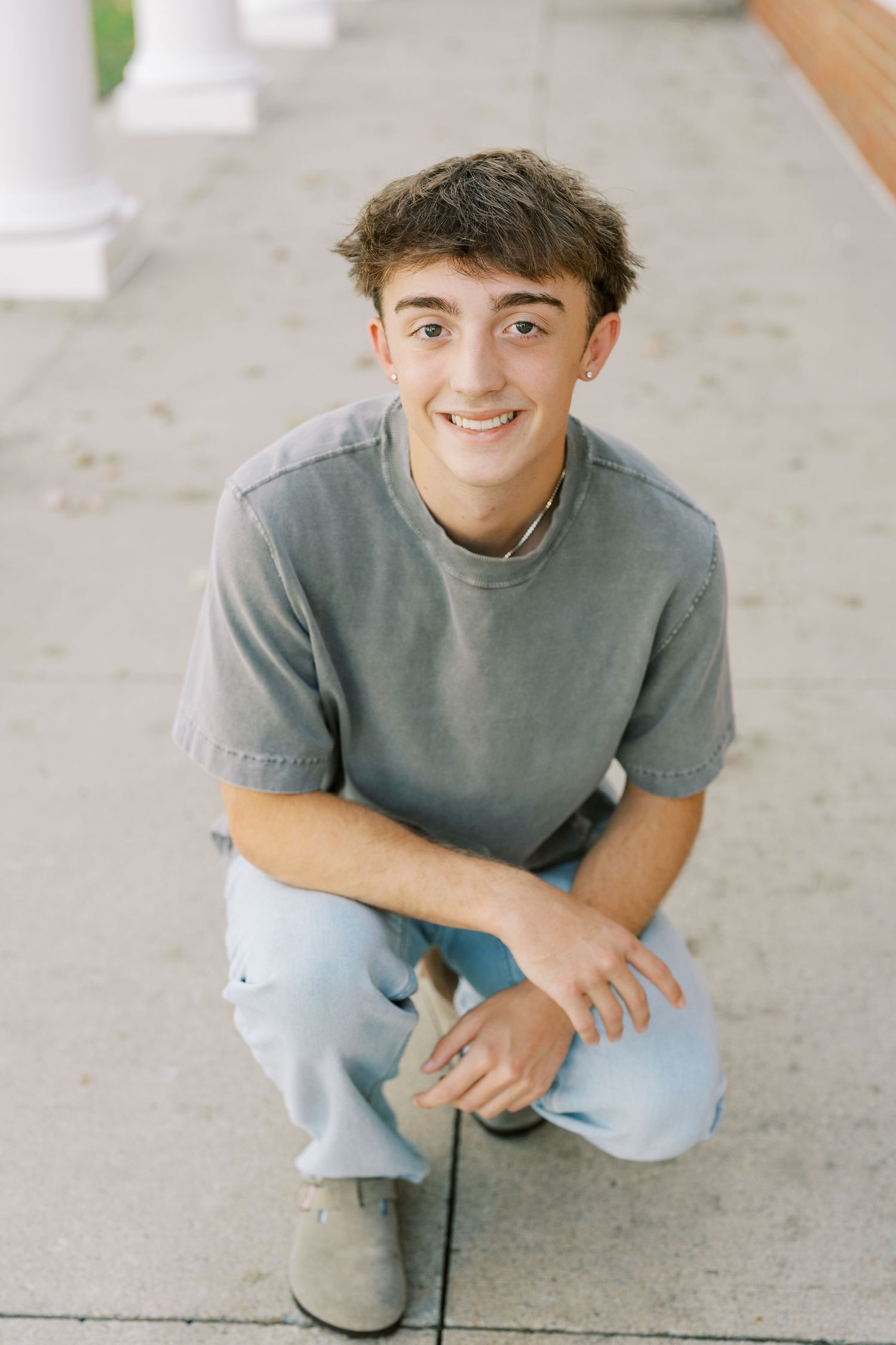 A person in a gray t-shirt and light blue jeans sits casually on concrete, shown in a series of similar poses.