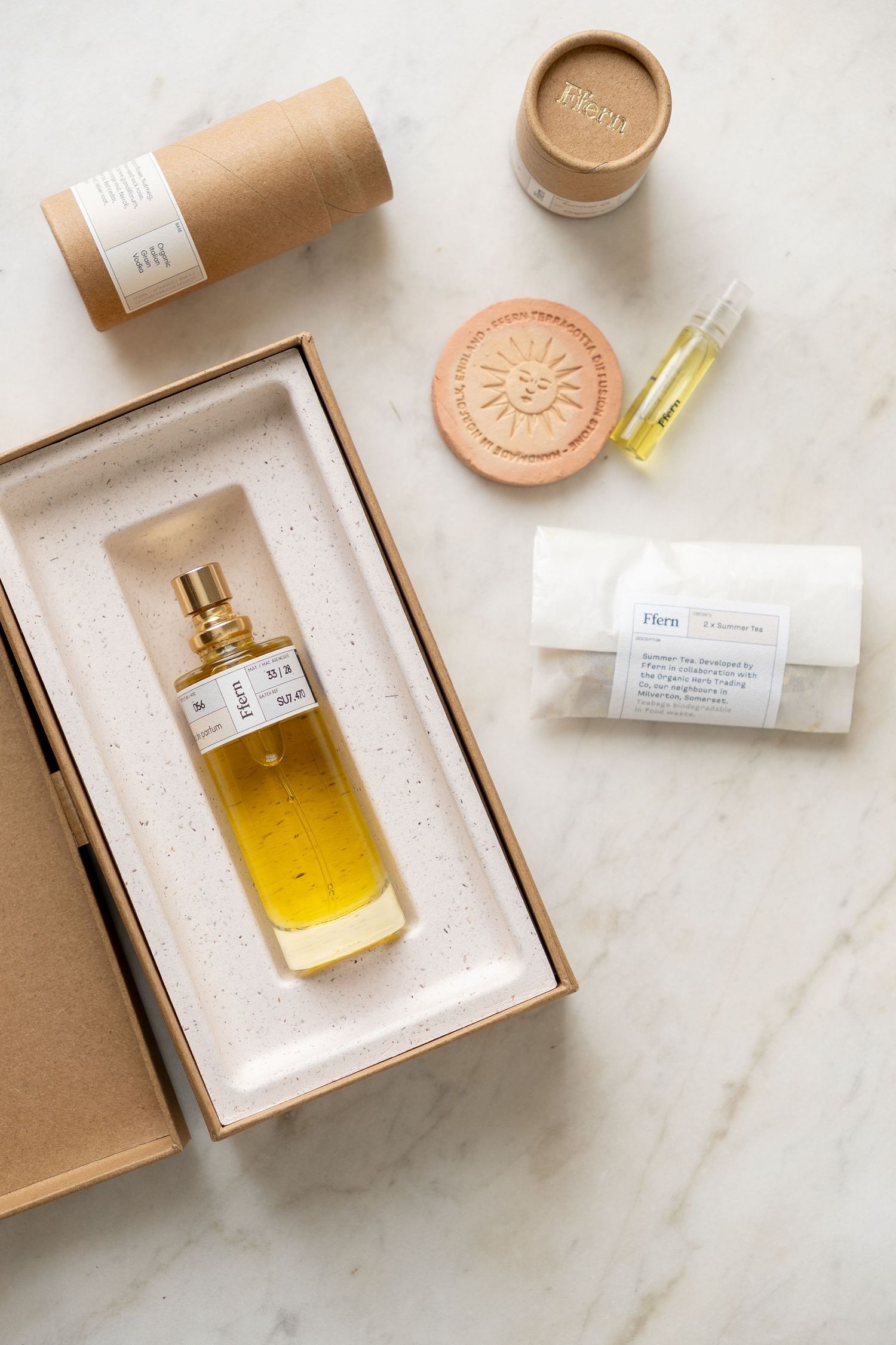 Luxury perfume bottle in amber glass displayed in kraft box with eco-friendly beauty accessories on marble surface.