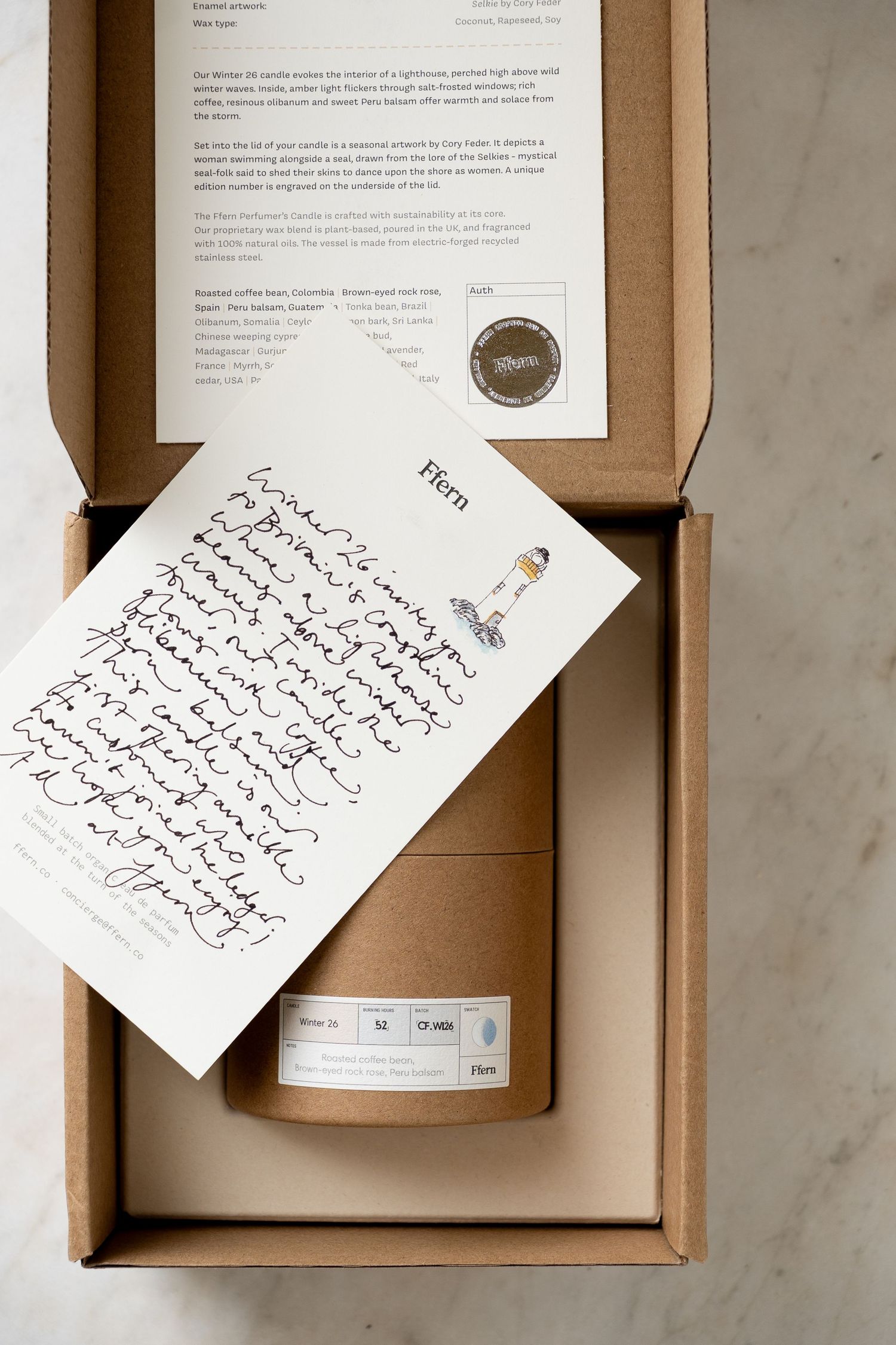 Kraft box with handwritten note and Fiiern branded candle packaging on marble surface.
