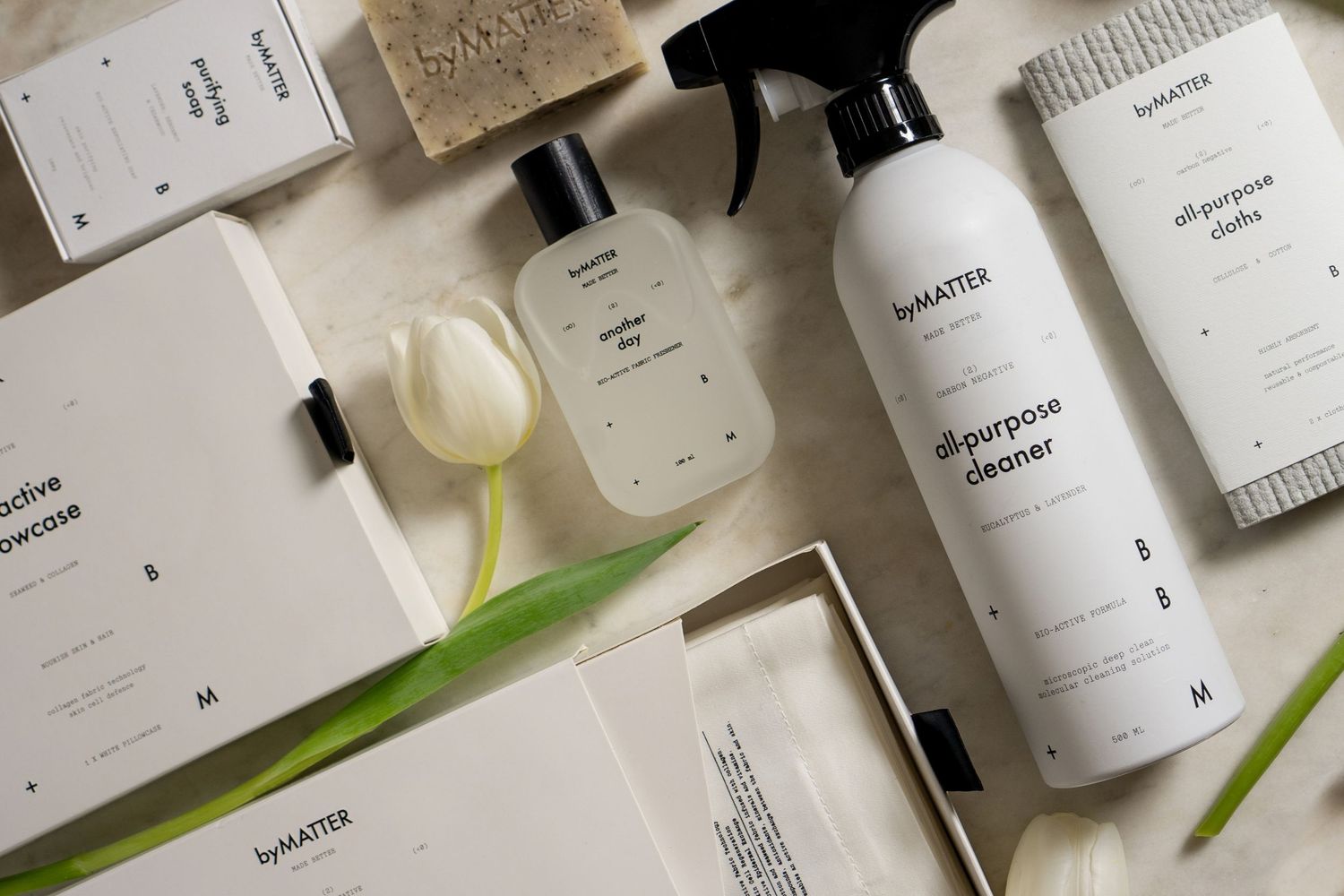 Flatlay of byMATTER home products including cleaner, perfume, and packaging with a white tulip.