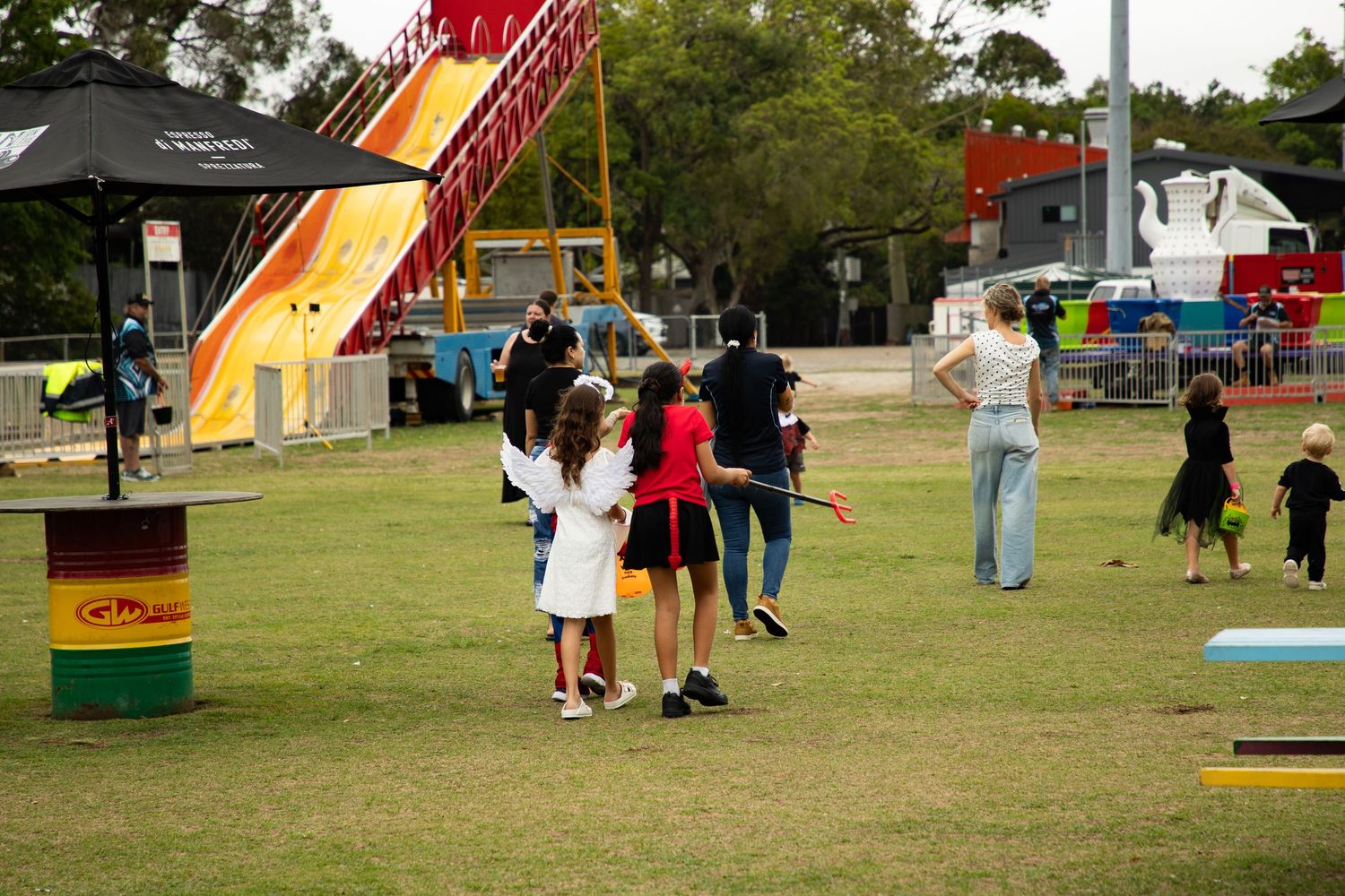Children and families enjoy carnival rides and activities at an outdoor Halloween community event.