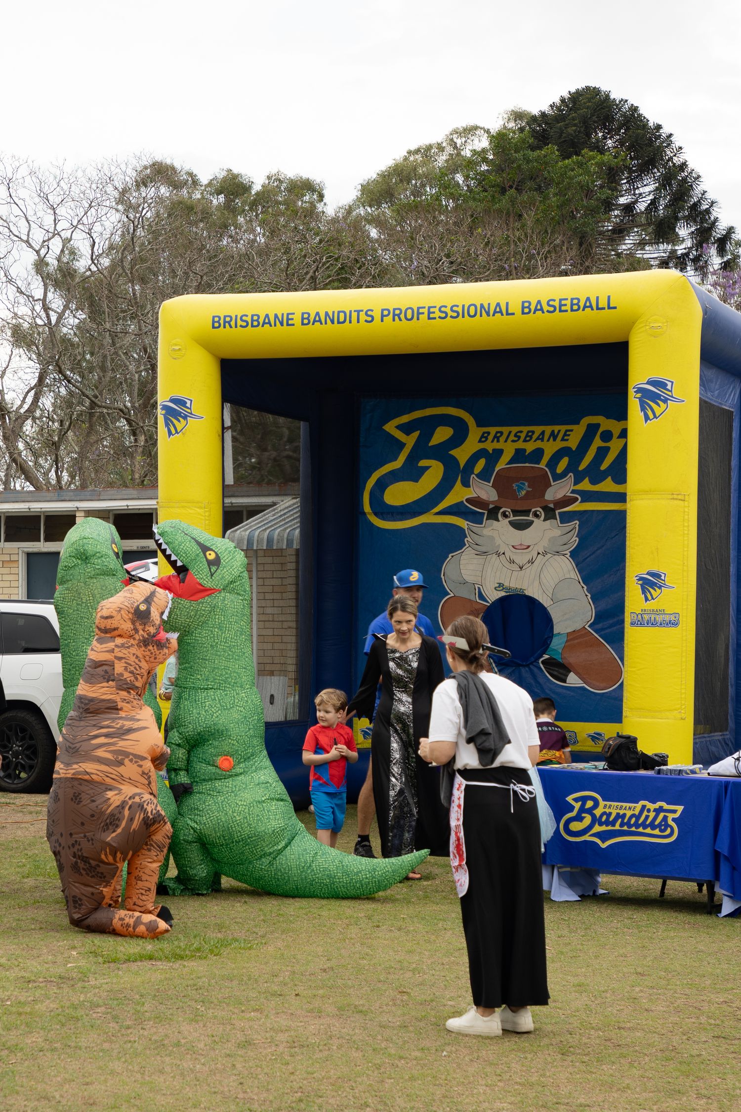 Brisbane Bandits Professional Baseball inflatable booth with dinosaur costume characters at outdoor event.
