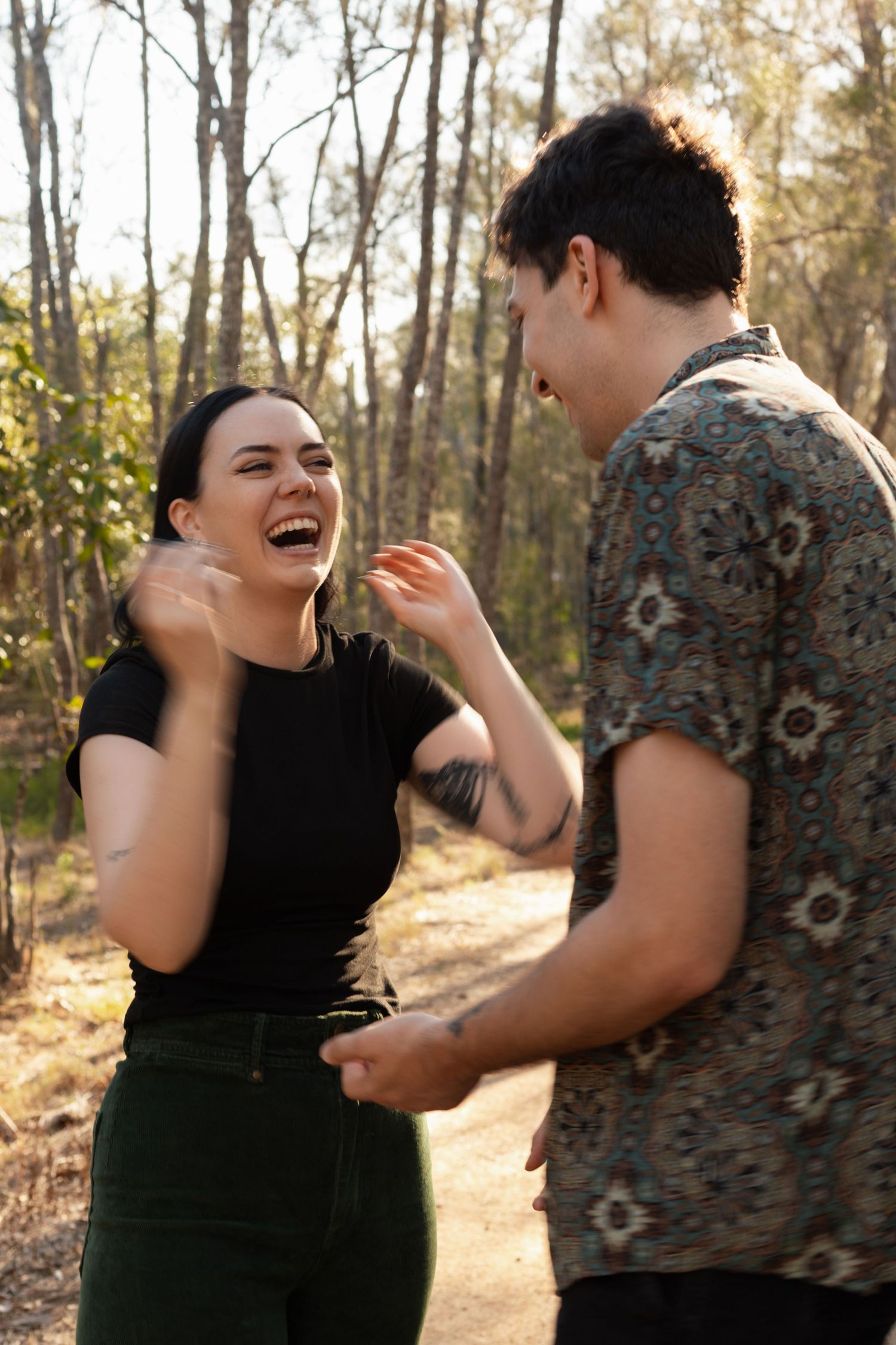 Laughing couple playfully interacting together on a bright sunny forest path.