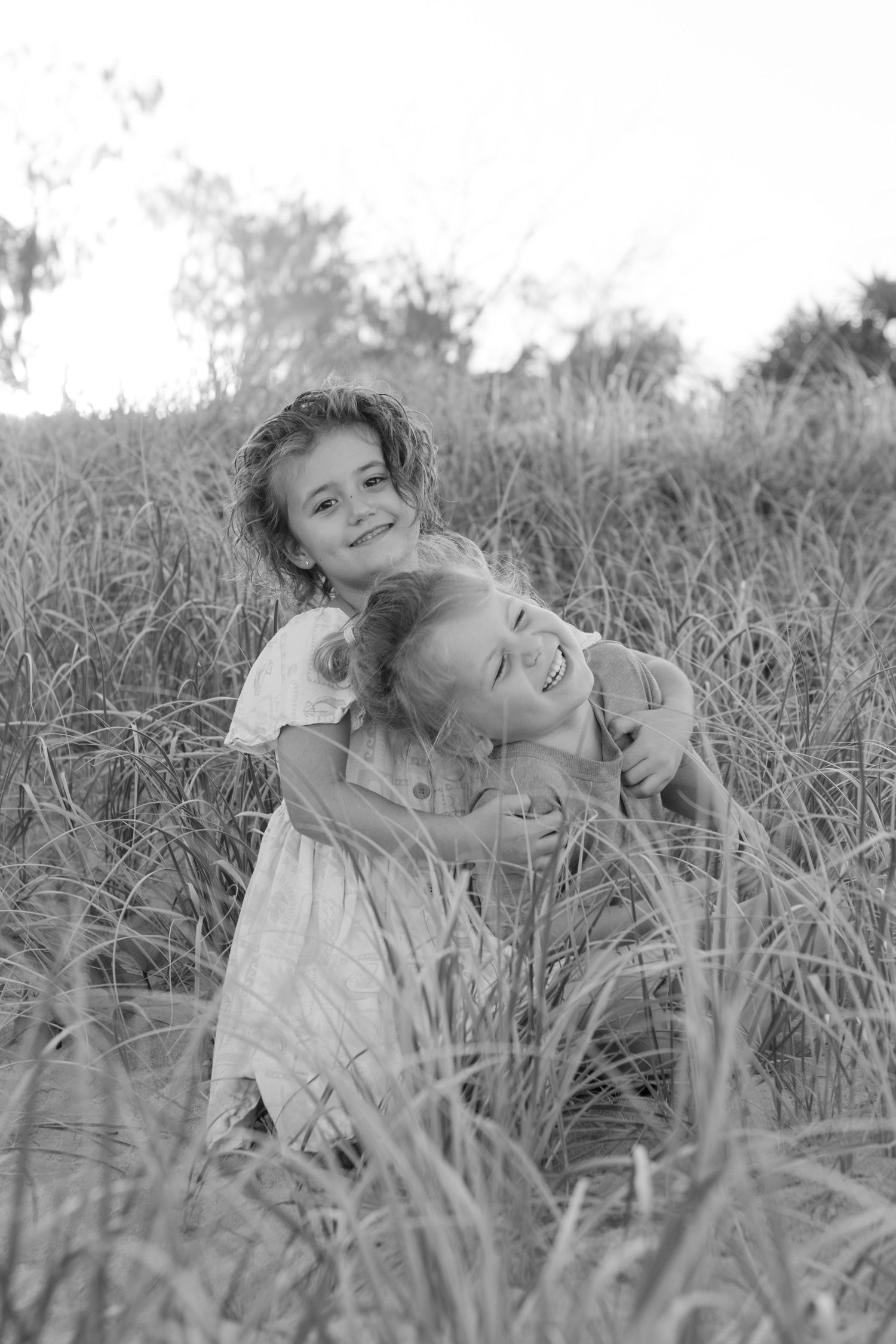 Two children laughing together during an outdoor family photo shoot.
