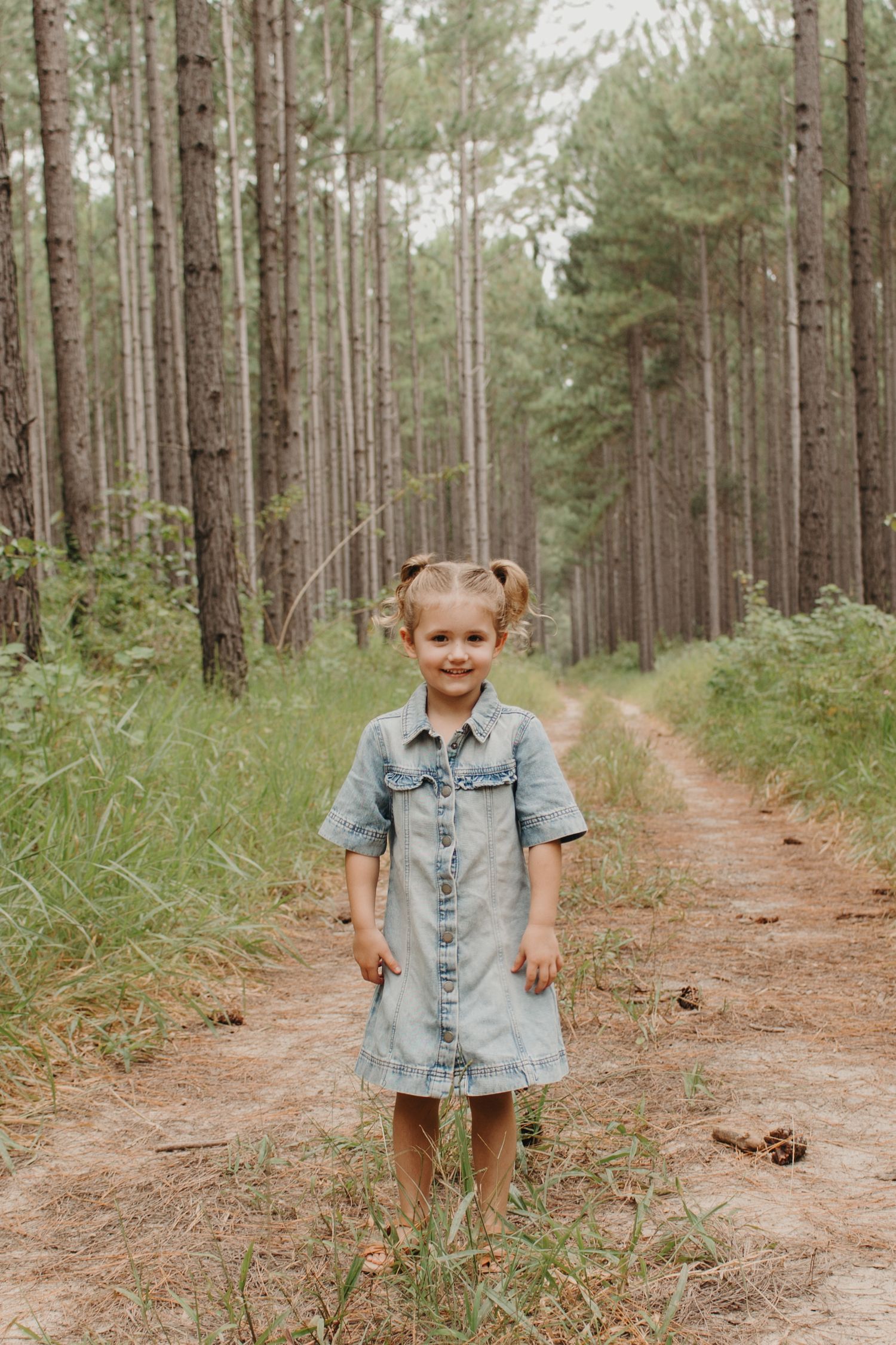 Toddler standing barefoot on a forest trail during a family photography session.