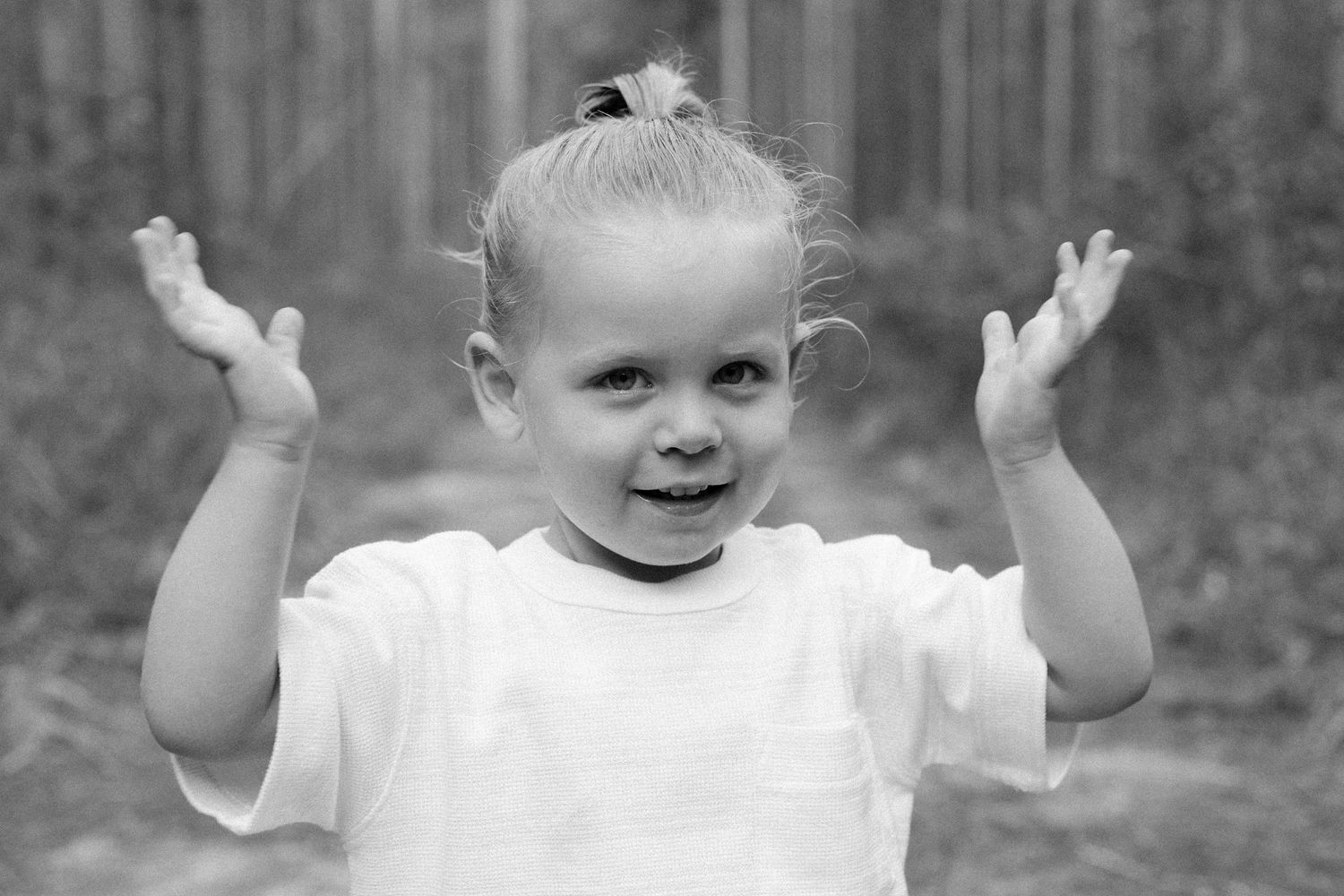 Toddler smiling outdoors during a family photography session.