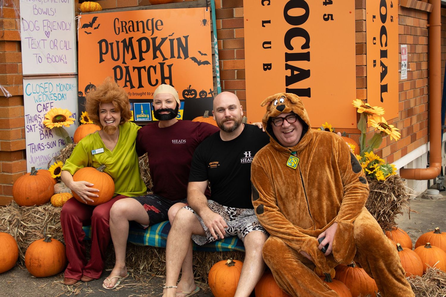 Four people in Scooby-Doo Halloween costumes posing at the Grange Pumpkin Patch event outside social club.