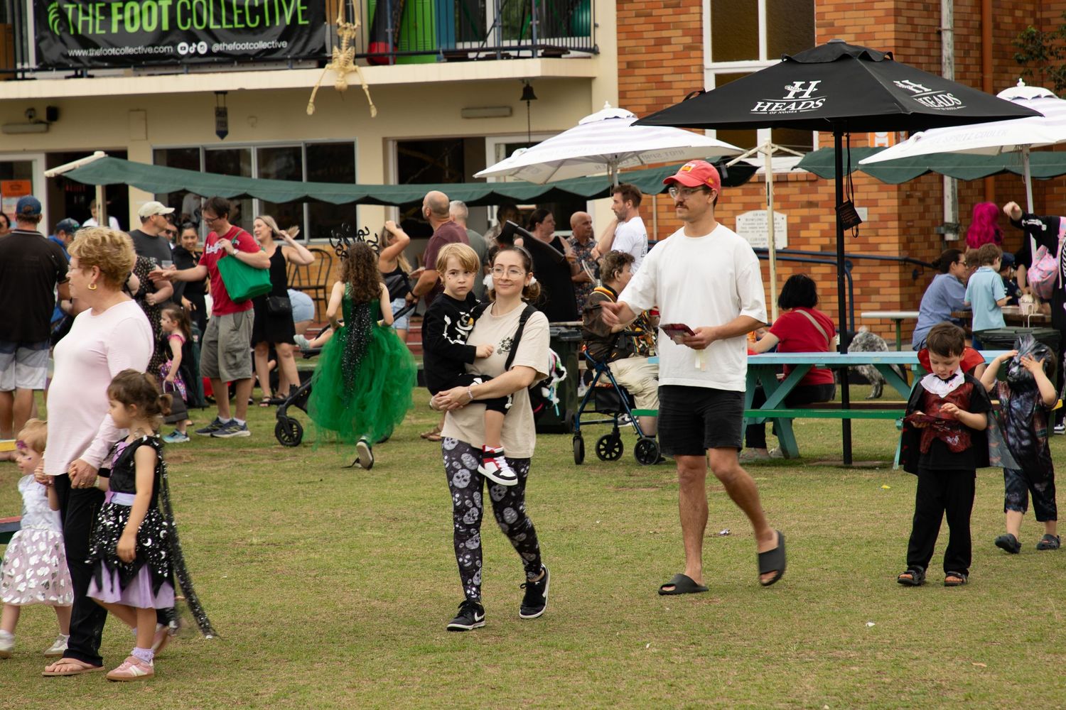 Families with children in Halloween costumes enjoy an outdoor Halloween community festival event.