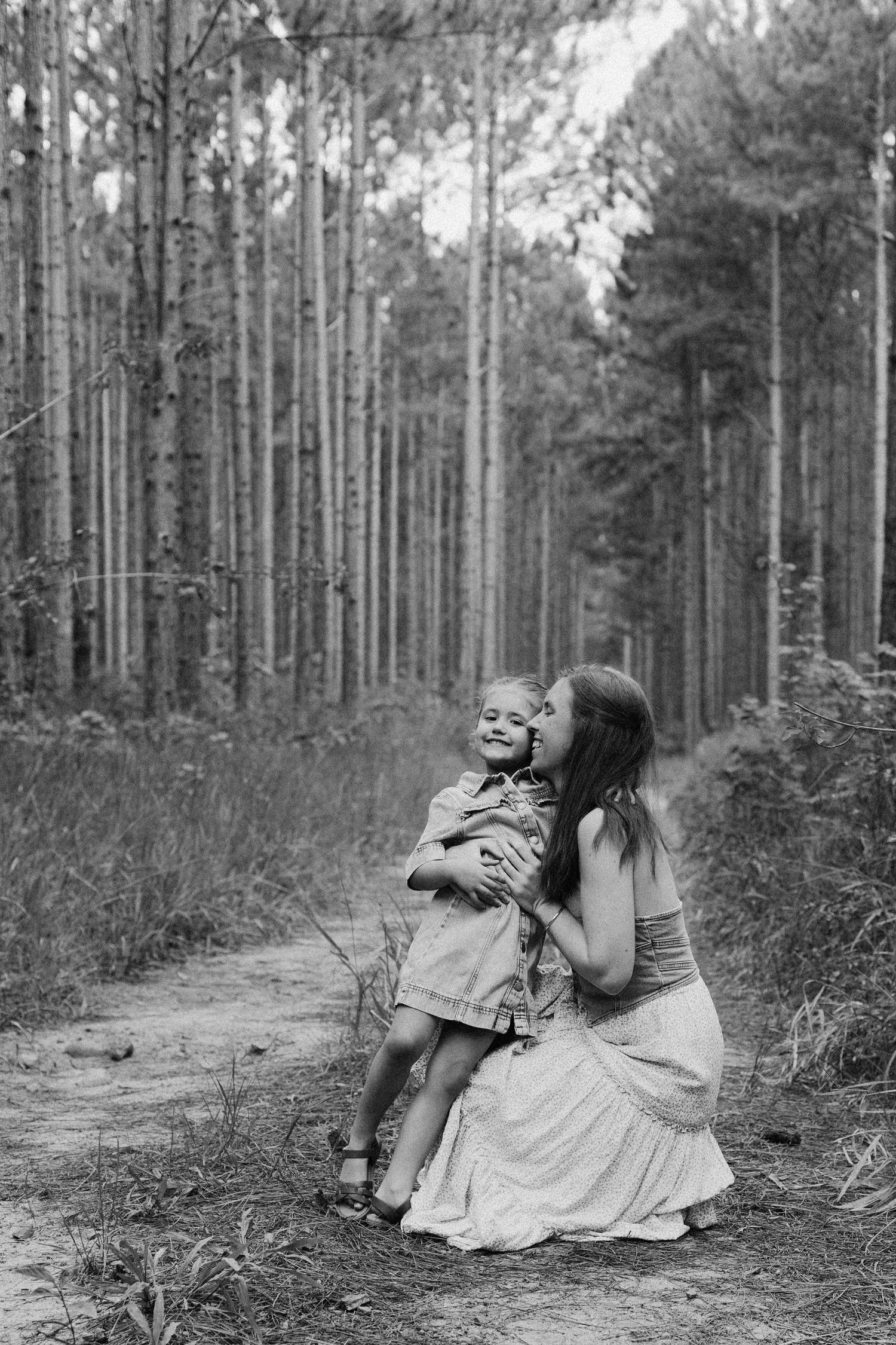 Mother hugging child on a forest trail during an outdoor family photo session.