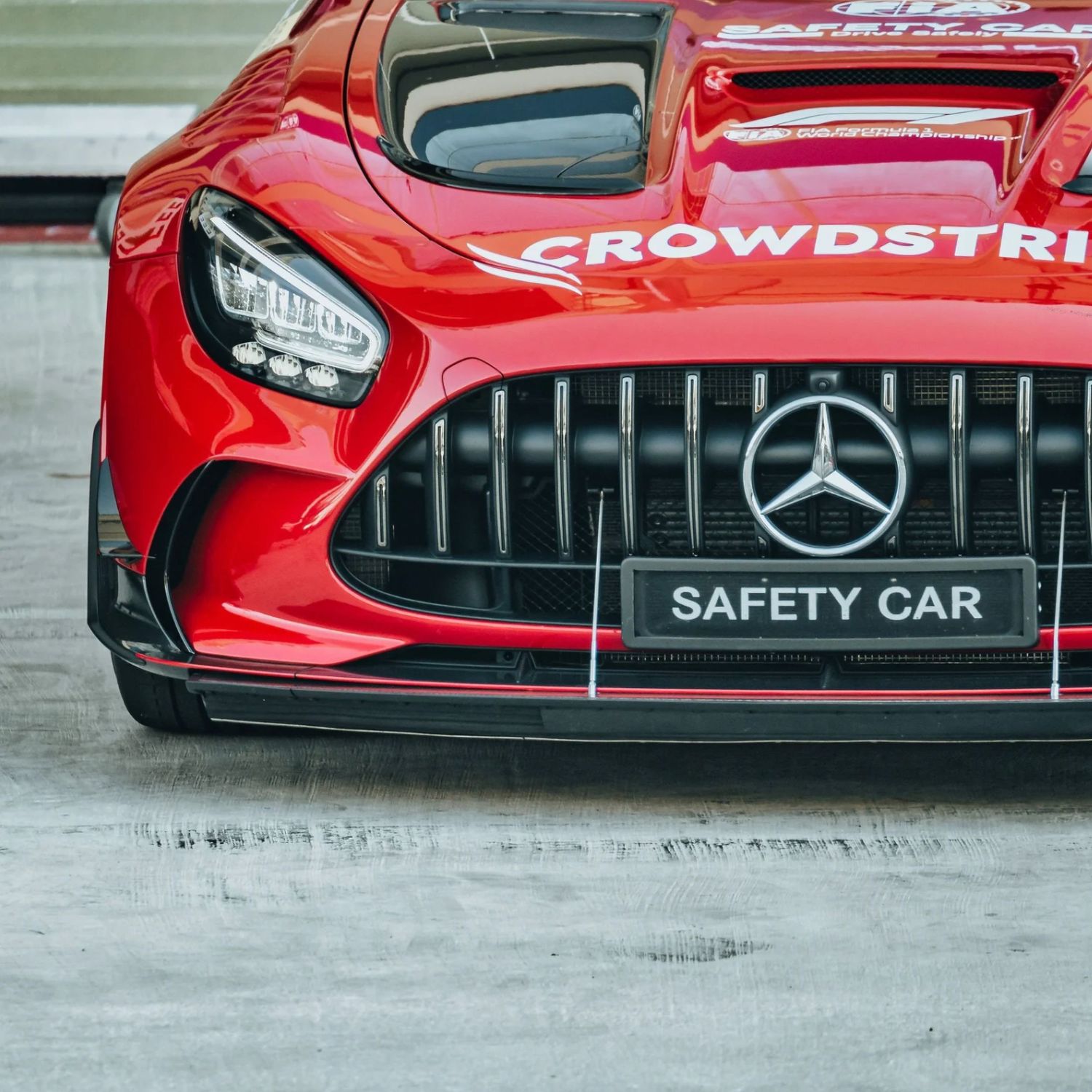 Red Mercedes-AMG GT Safety Car with CrowdStrike livery, featuring iconic three-pointed star grille at Formula 1 circuit.