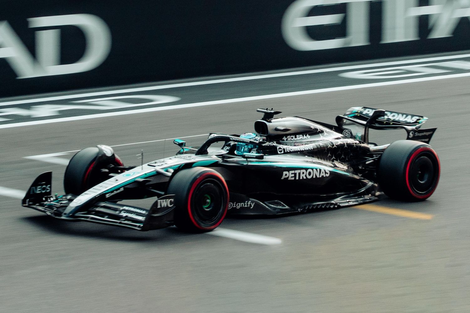 Mercedes-AMG Petronas Formula 1 car racing past Etihad Airways signage at Abu Dhabi Grand Prix.