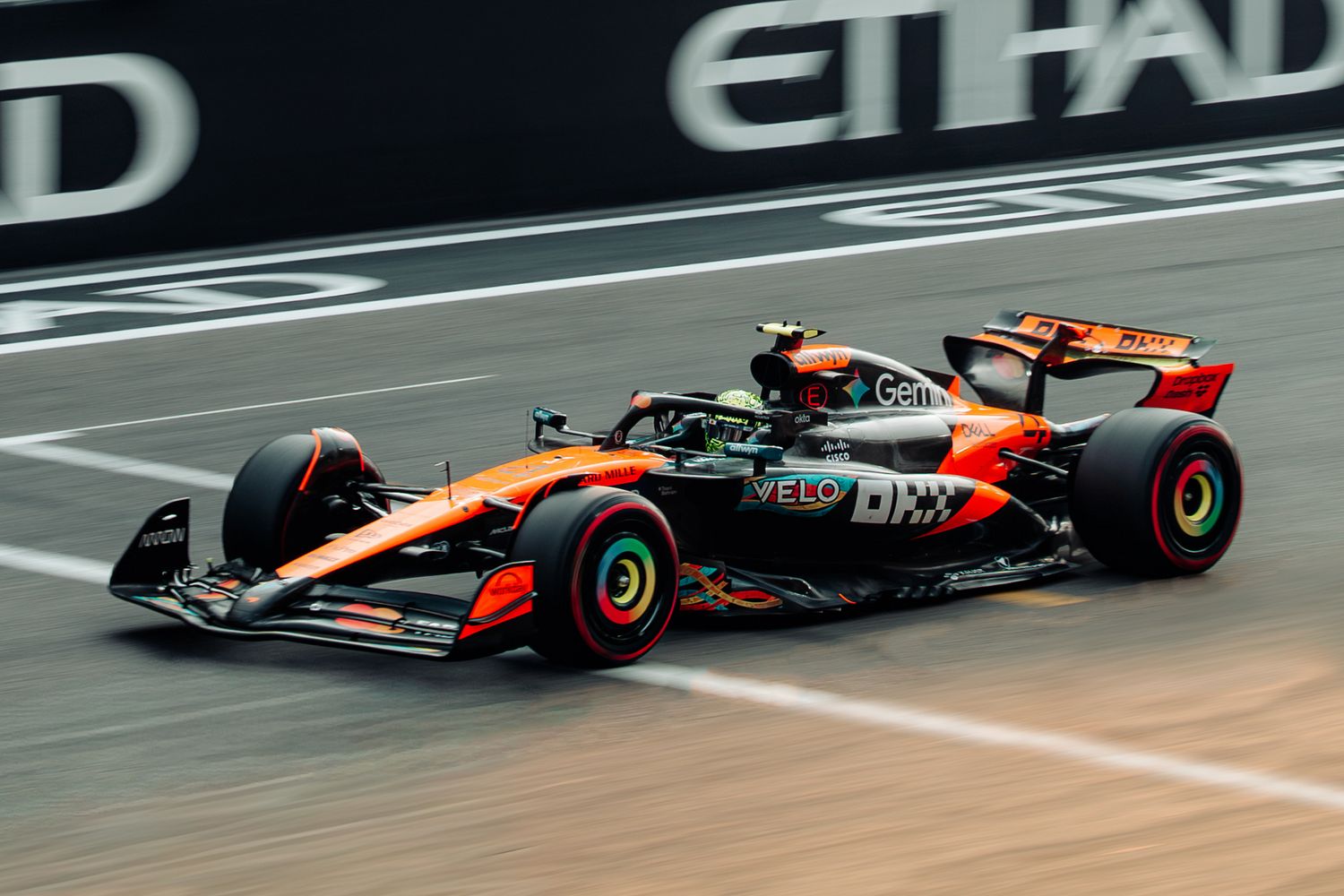 McLaren Formula 1 car in vibrant orange livery competing at Abu Dhabi Grand Prix circuit.