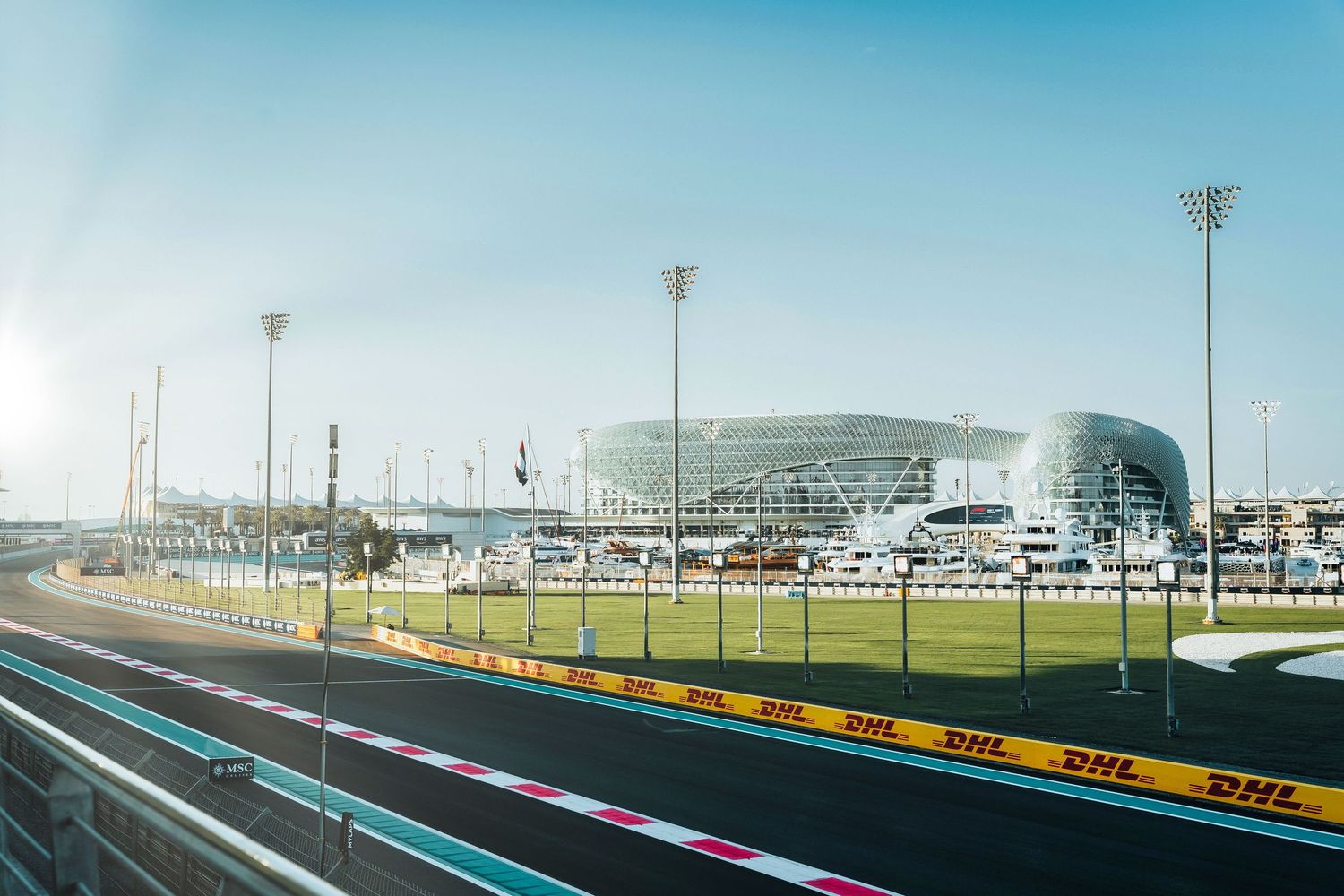 Yas Marina Circuit Formula 1 track with iconic Yas Hotel in background on sunny day.