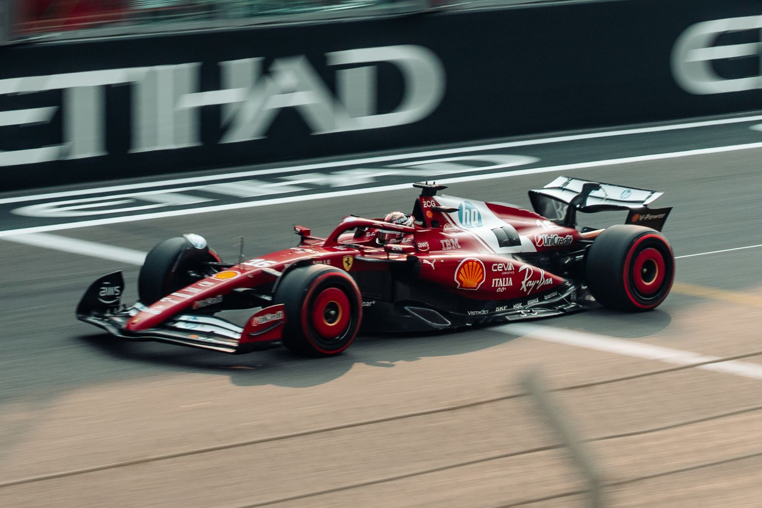 Ferrari F1 car racing on track at Abu Dhabi Grand Prix with Etihad Airways branding in background.