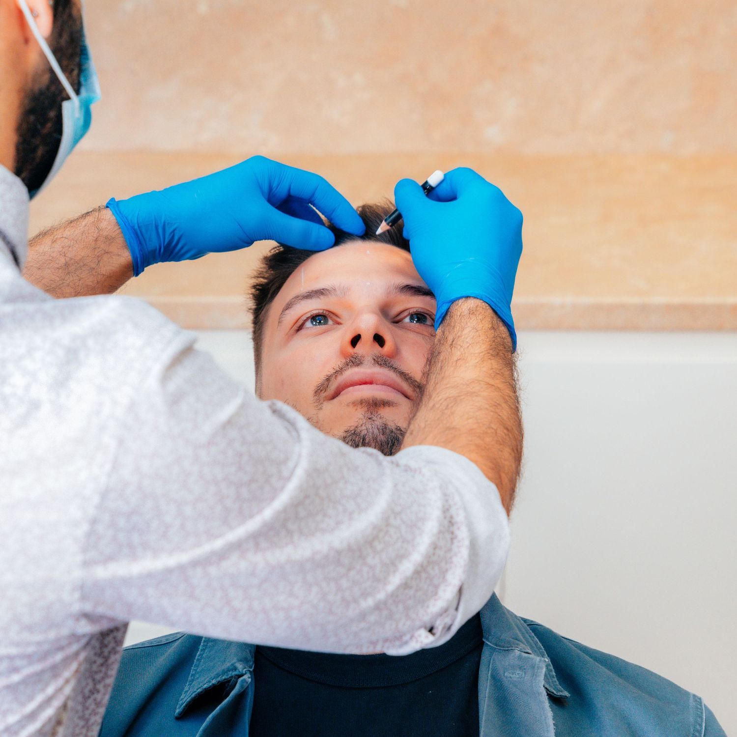 Medical professional wearing blue gloves performing a facial injection treatment on a male patient.