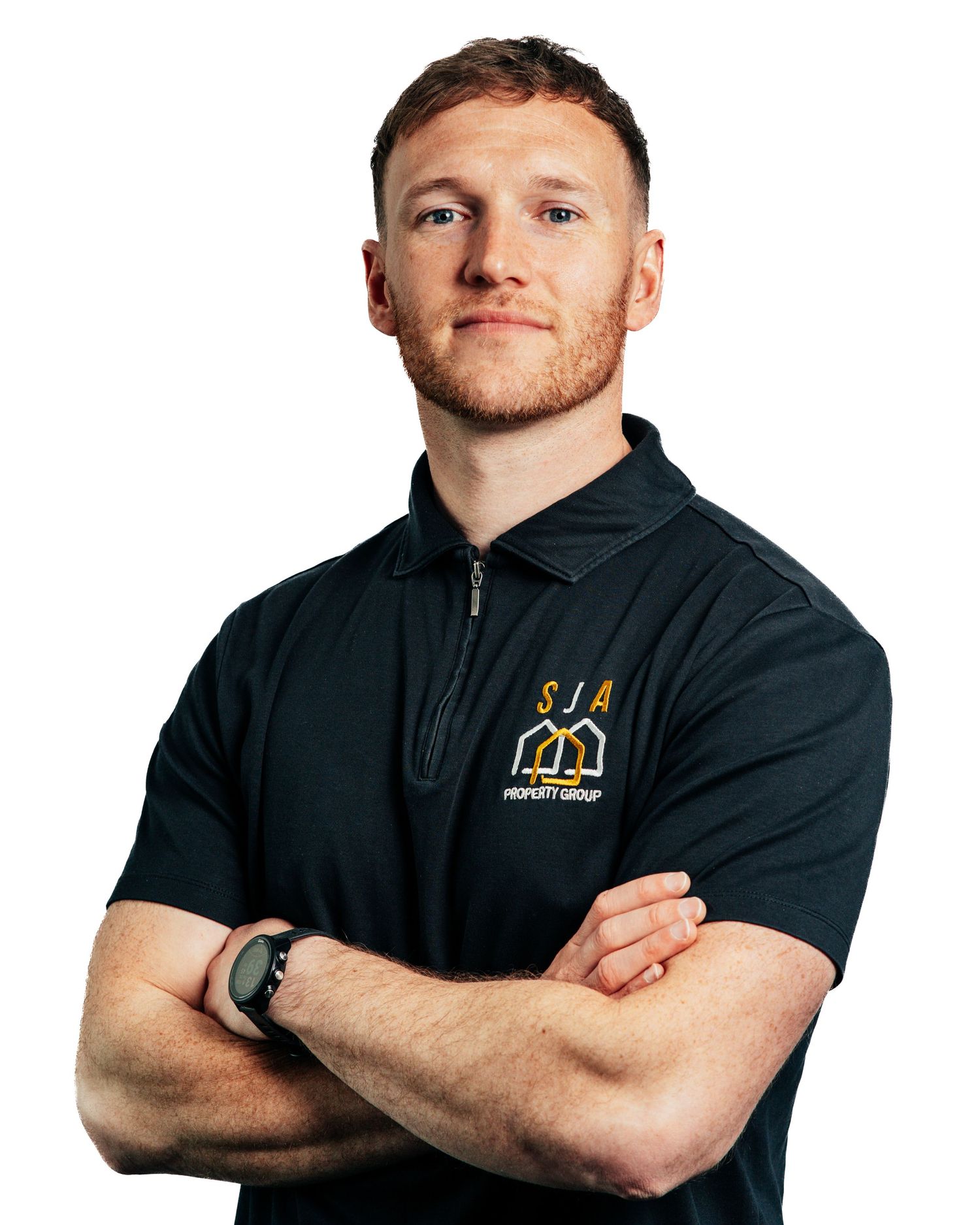 Man in black SJA Property Group zip polo shirt standing with arms crossed wearing a watch.