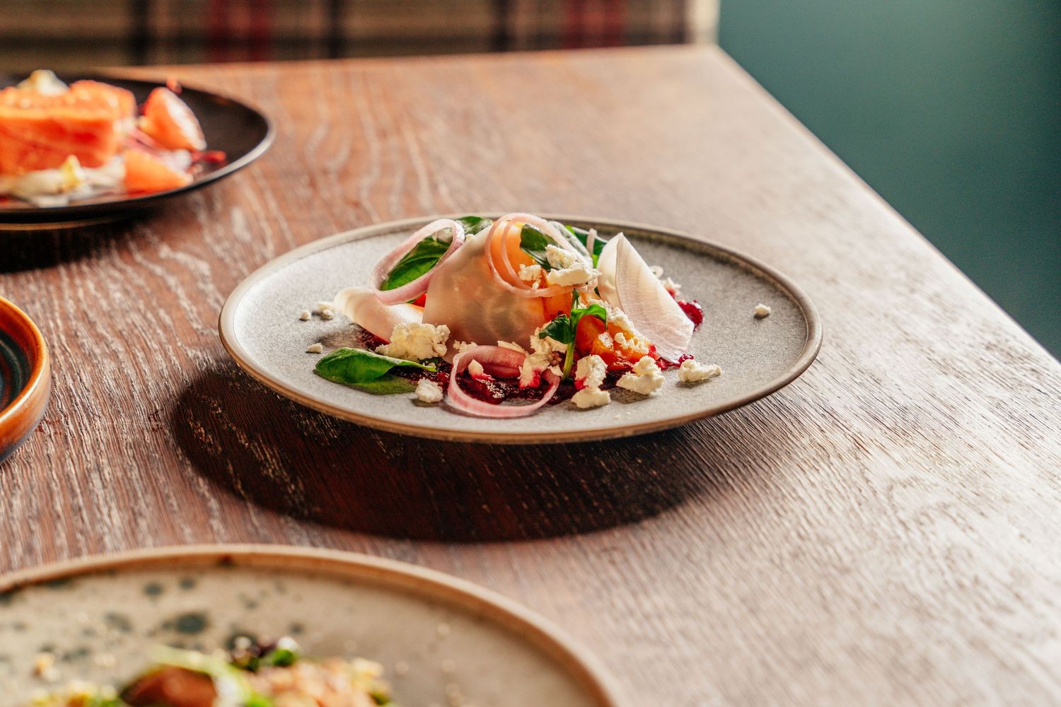 A delicate seafood salad with fresh herbs and red onion served on a grey ceramic plate on a wooden table.