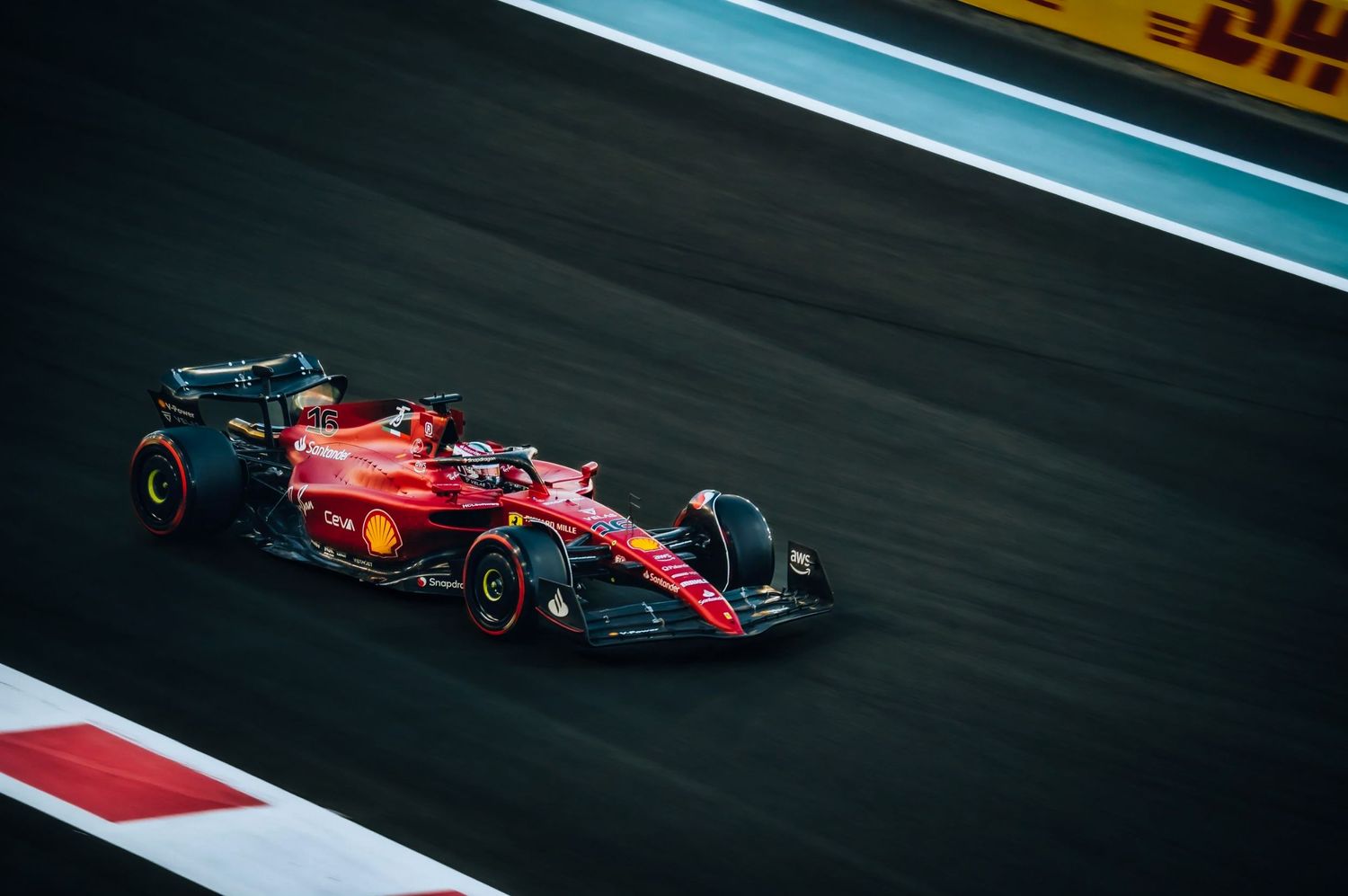 Ferrari F1 racing car speeding on track at Abu Dhabi Grand Prix circuit under dramatic dark sky.