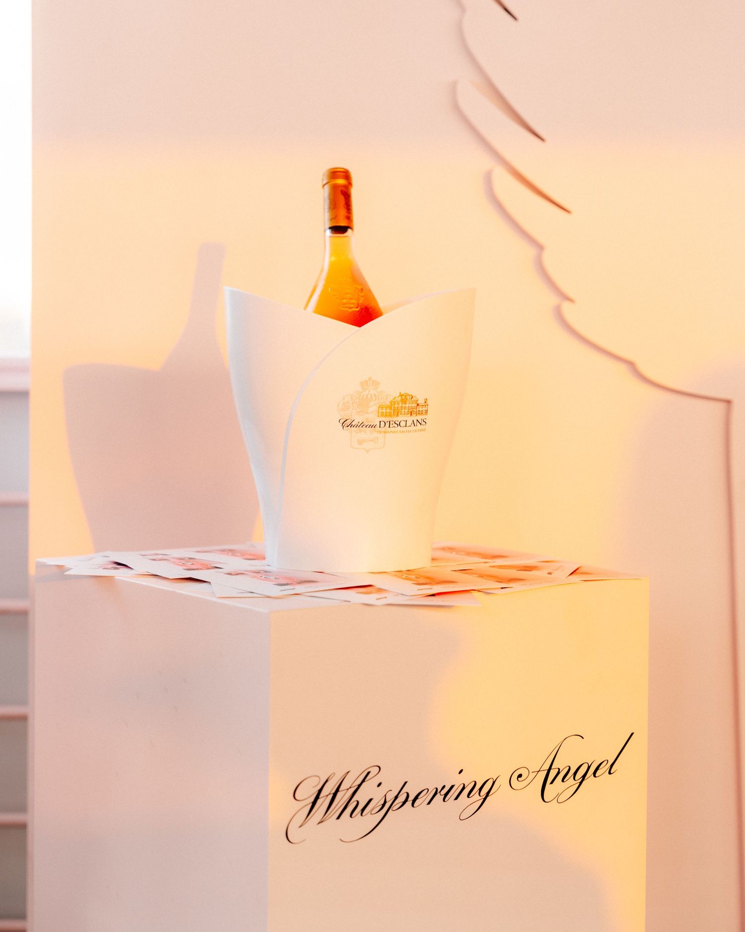 Bottle of Whispering Angel rosé wine chilling in an ice bucket on a glowing white display pedestal.