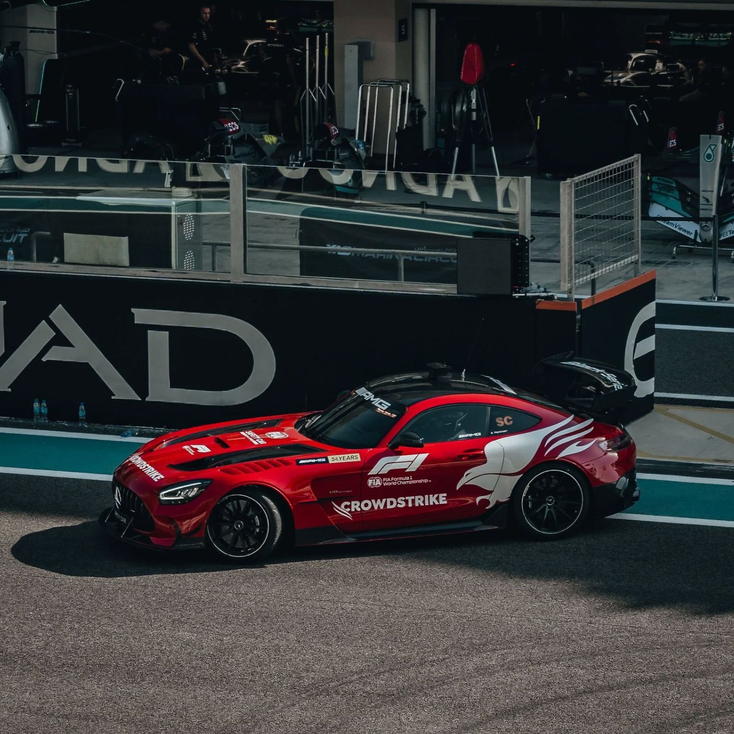 Red Mercedes-AMG GT F1 safety car with CrowdStrike livery on pit lane at Abu Dhabi Grand Prix circuit.