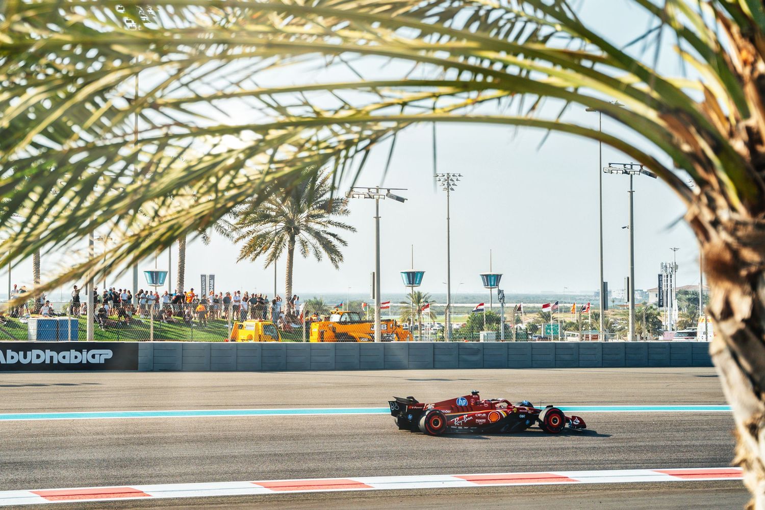 Ferrari Formula 1 car speeding along Abu Dhabi Grand Prix circuit framed by palm trees.