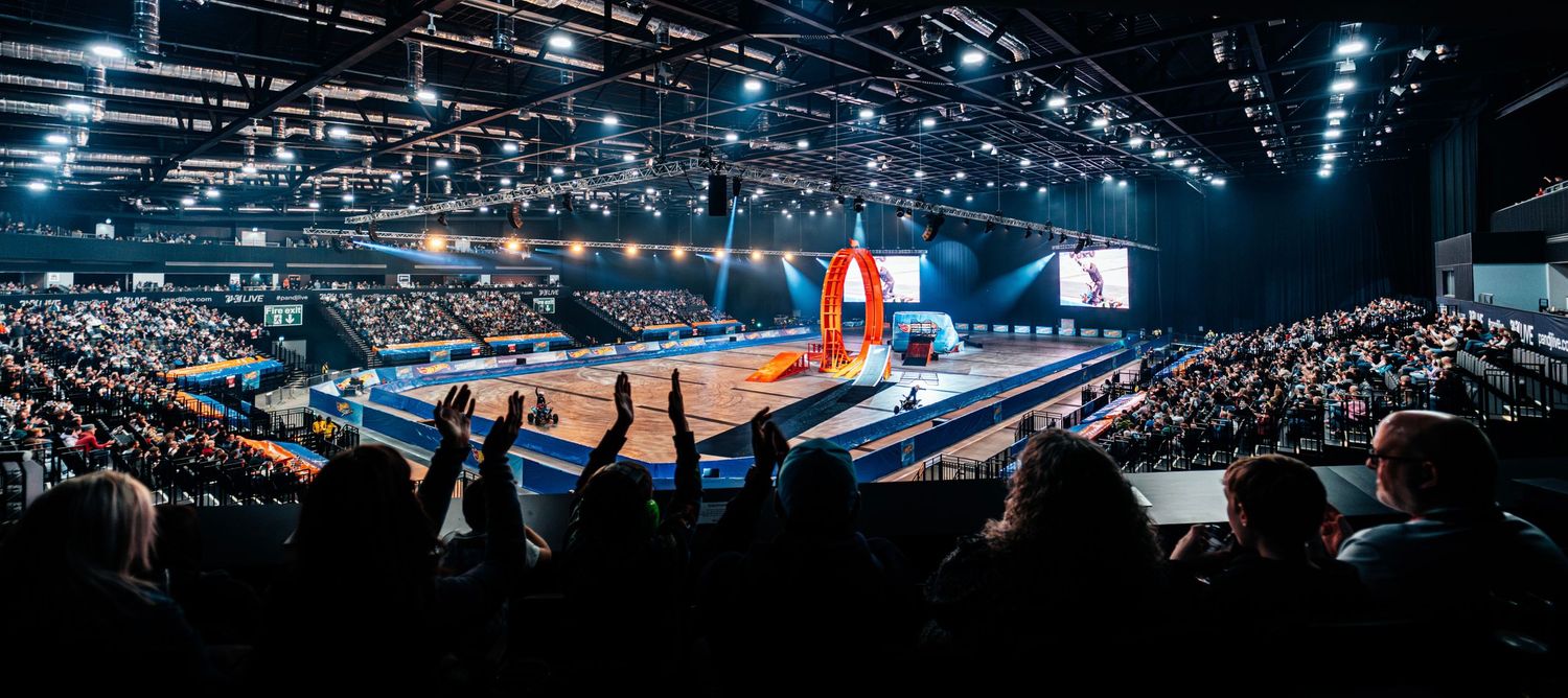 Panoramic view of a packed indoor arena with crowds cheering at a large sporting or entertainment event.
