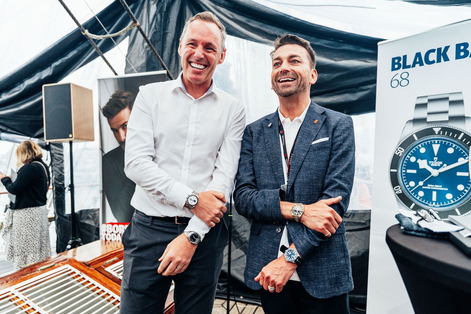Two smiling men posing at Black Bay 68 watch display booth at an event.