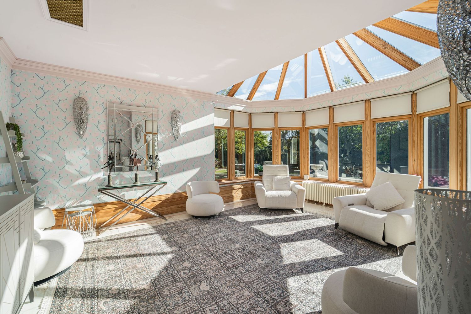Bright sunroom conservatory with curved skylights, white lounge chairs, and patterned grey carpet flooring.