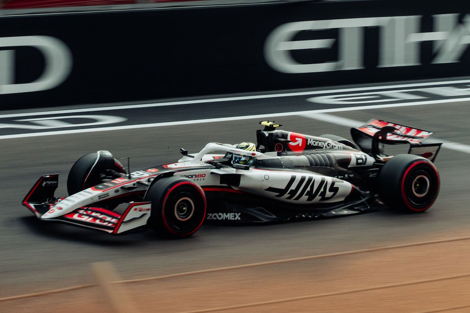 Haas F1 racing car with MoneyGram livery competing at Abu Dhabi Grand Prix on Yas Marina Circuit.
