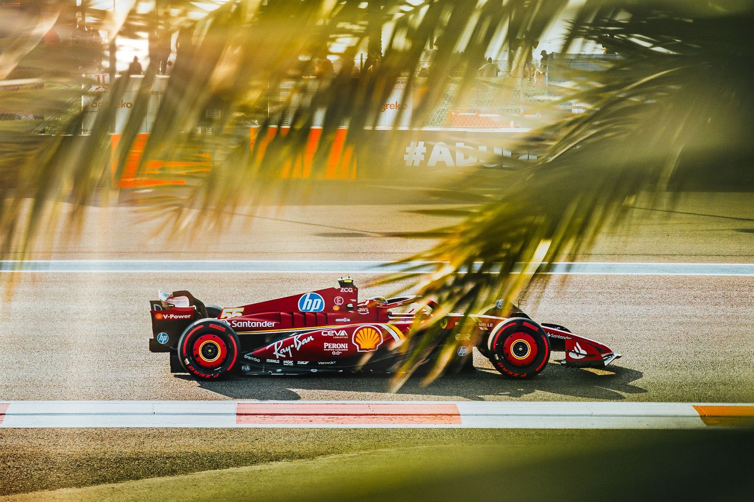 Ferrari Formula 1 car racing past in golden light at Abu Dhabi Grand Prix circuit.