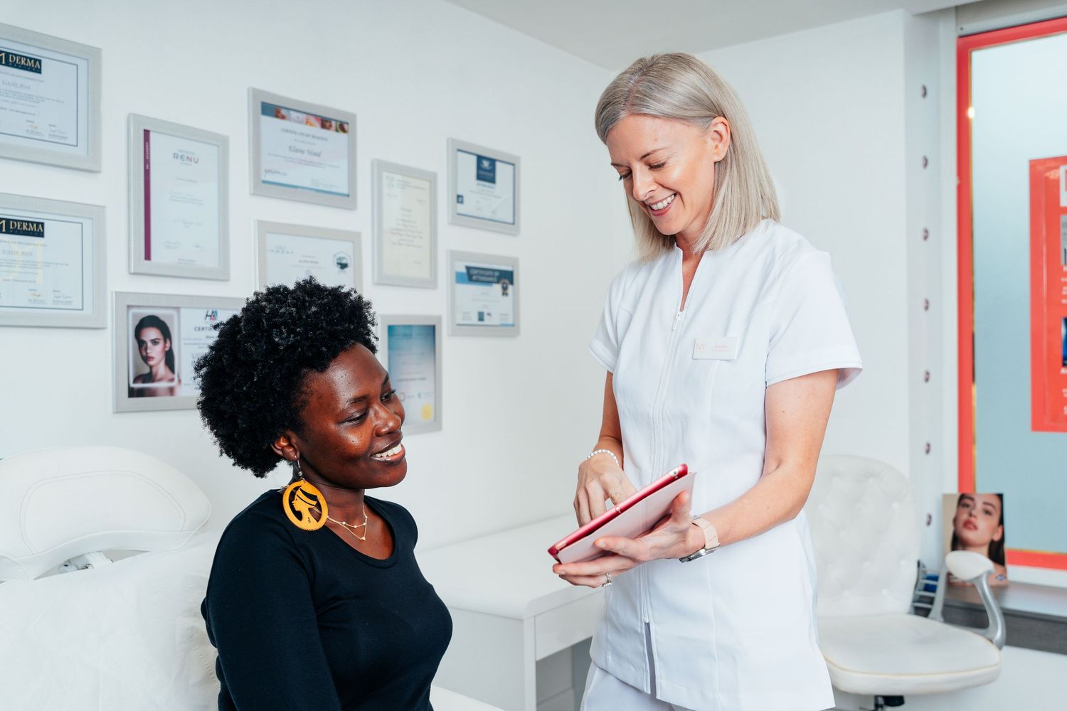 Healthcare professional in white uniform consulting with a seated female patient in a clinic.