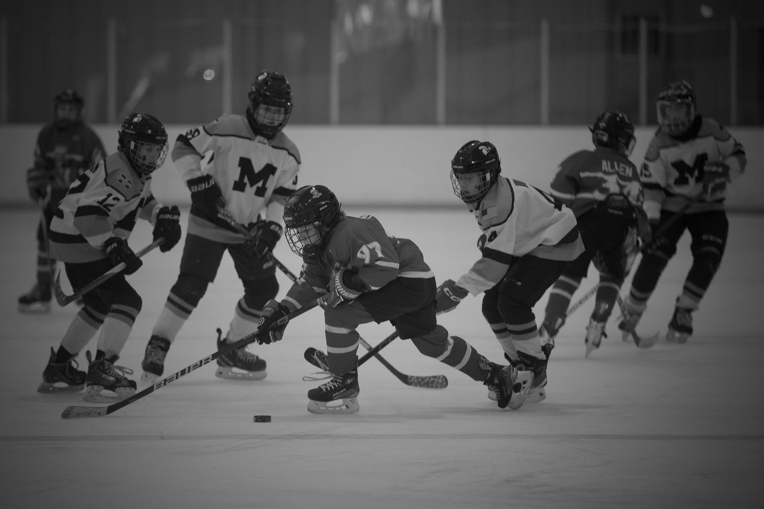 Youth hockey players battling for the puck in front of the net during a game in McFarland, Wisconsin