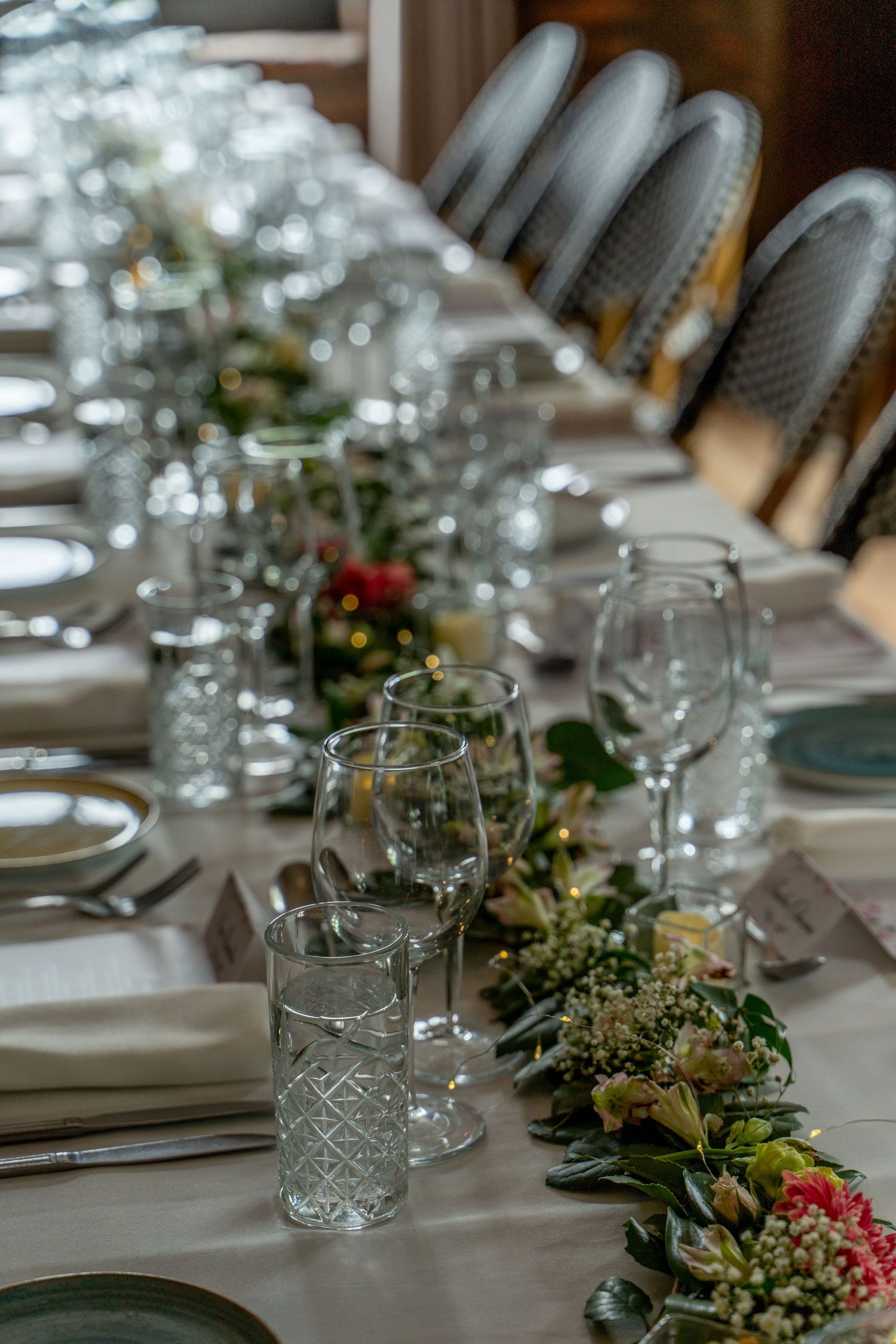 Elegant table setting with crystal glasses and greenery decorations for wedding reception.