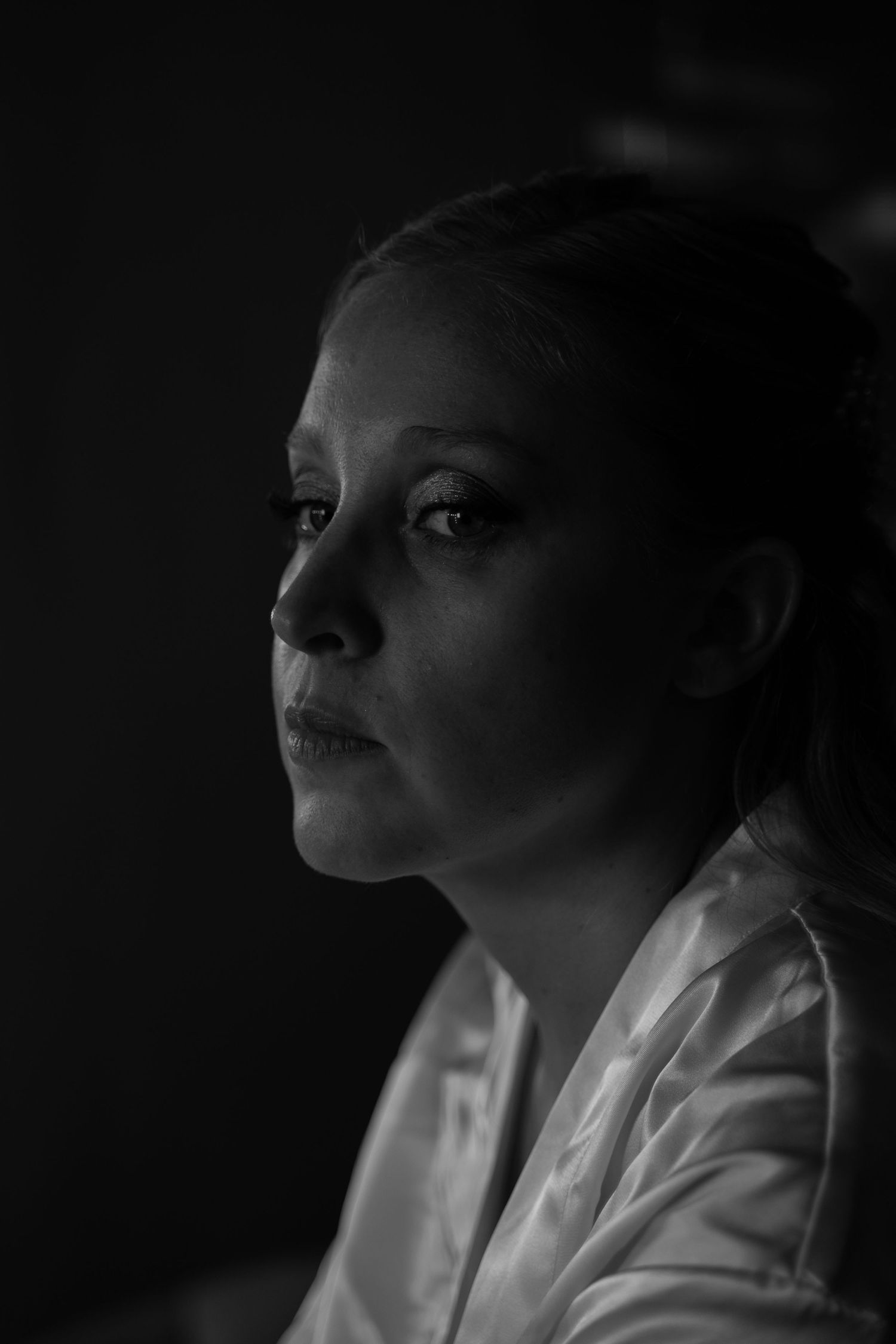 Dramatic black and white portrait in moody lighting against dark background.