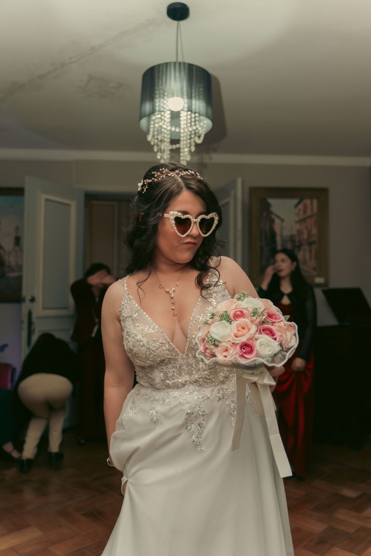 Bride in lace dress holds pink and white rose bouquet during reception.
