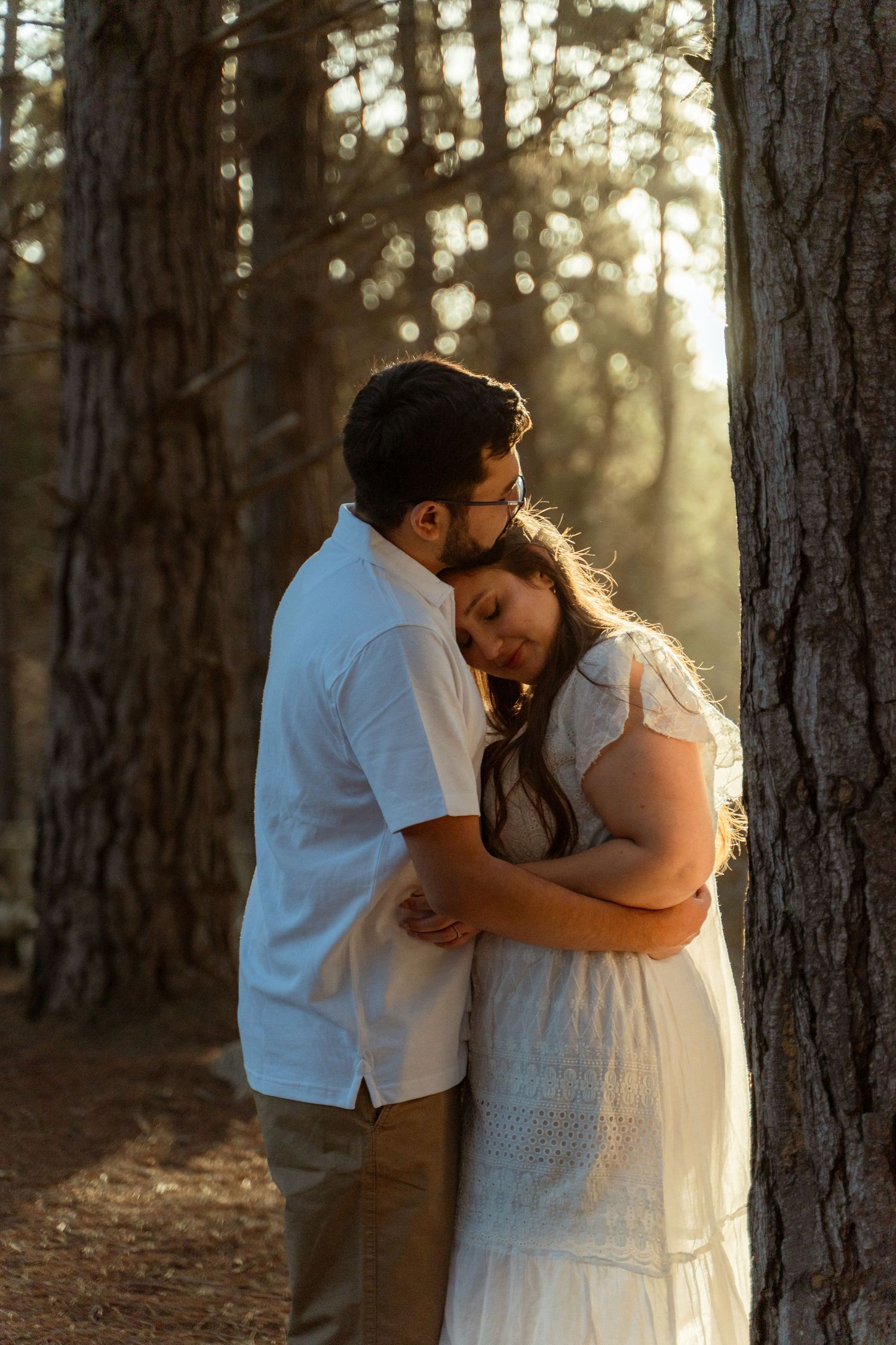 Intimate wedding portraits captured in a sunlit pine forest.