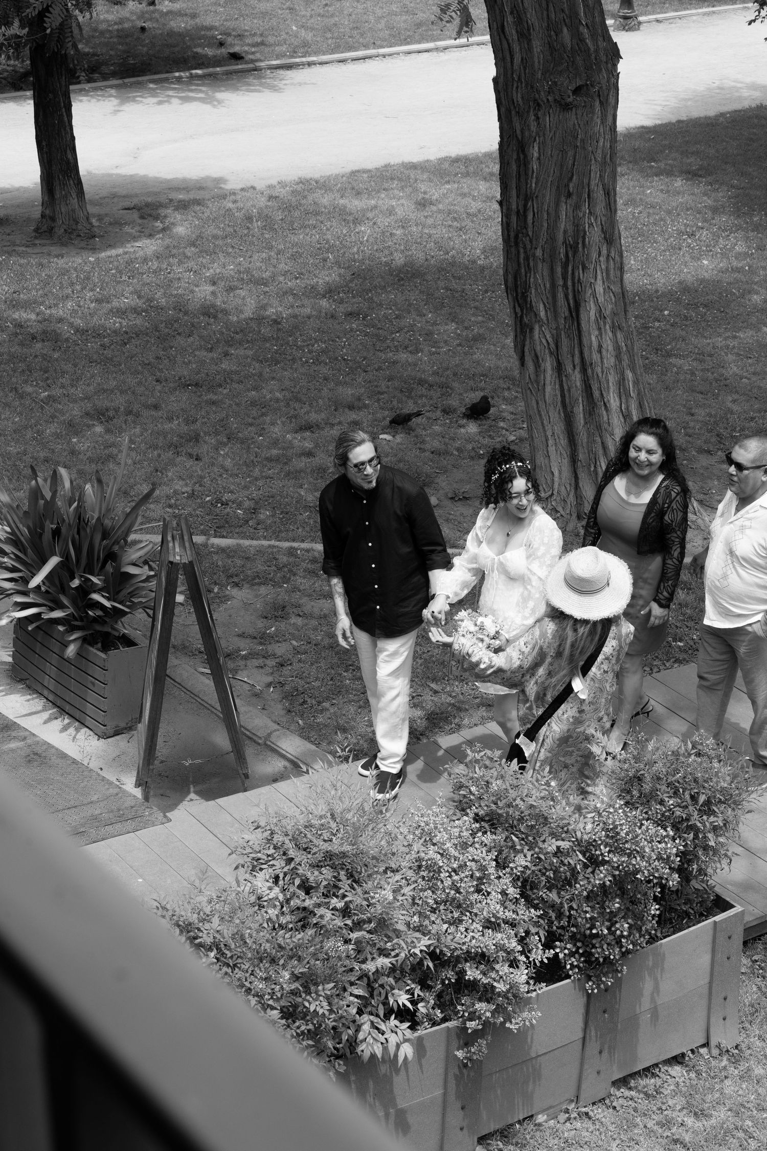 Black and white photo of wedding guests seated outdoors near planters.