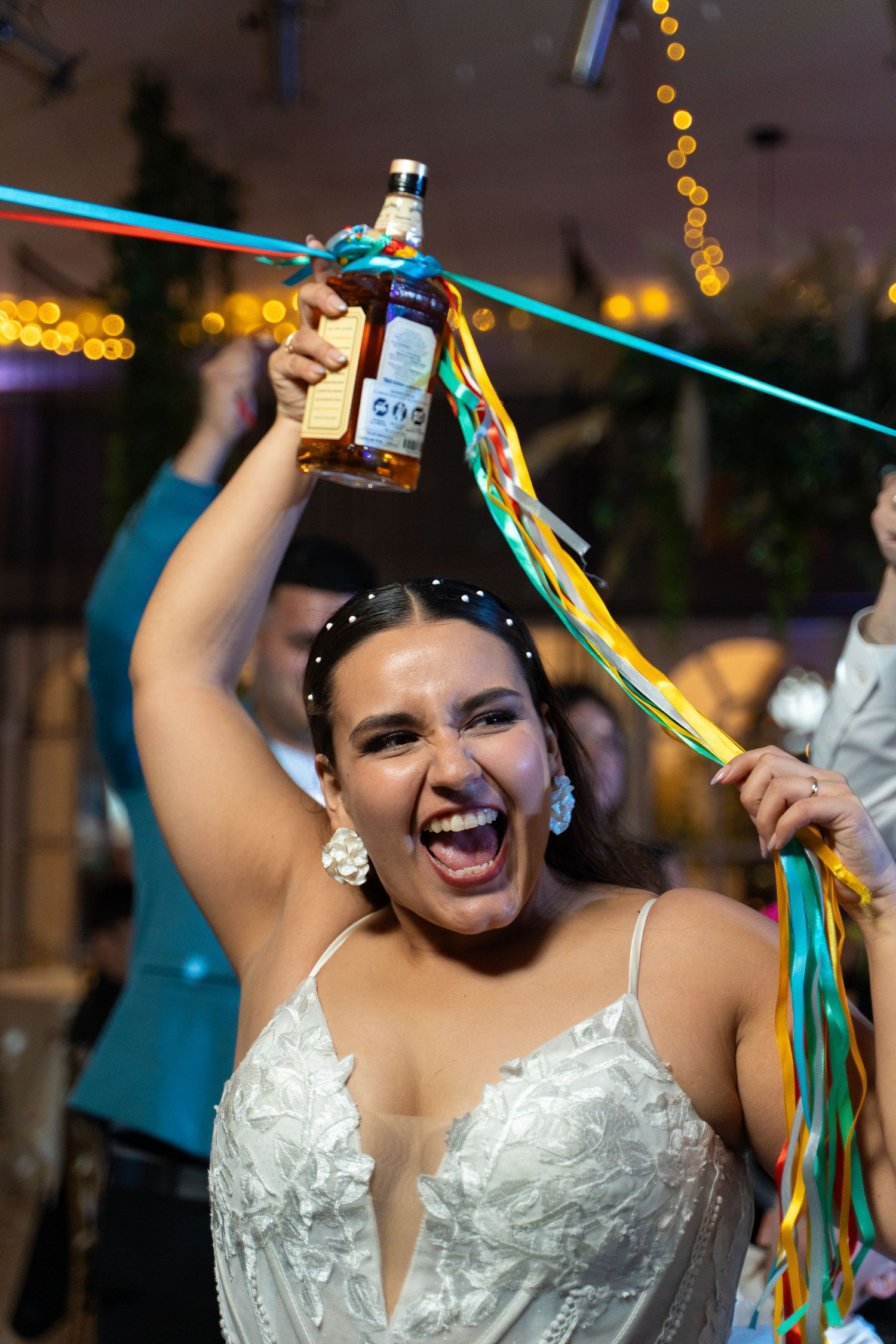 A bride dances joyfully with colorful ribbons at wedding reception.
