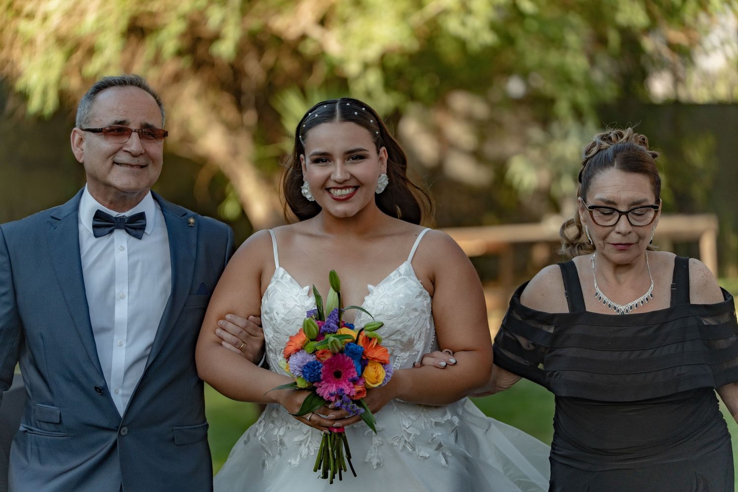 Wedding party poses together outdoors with colorful bouquets and formal attire.