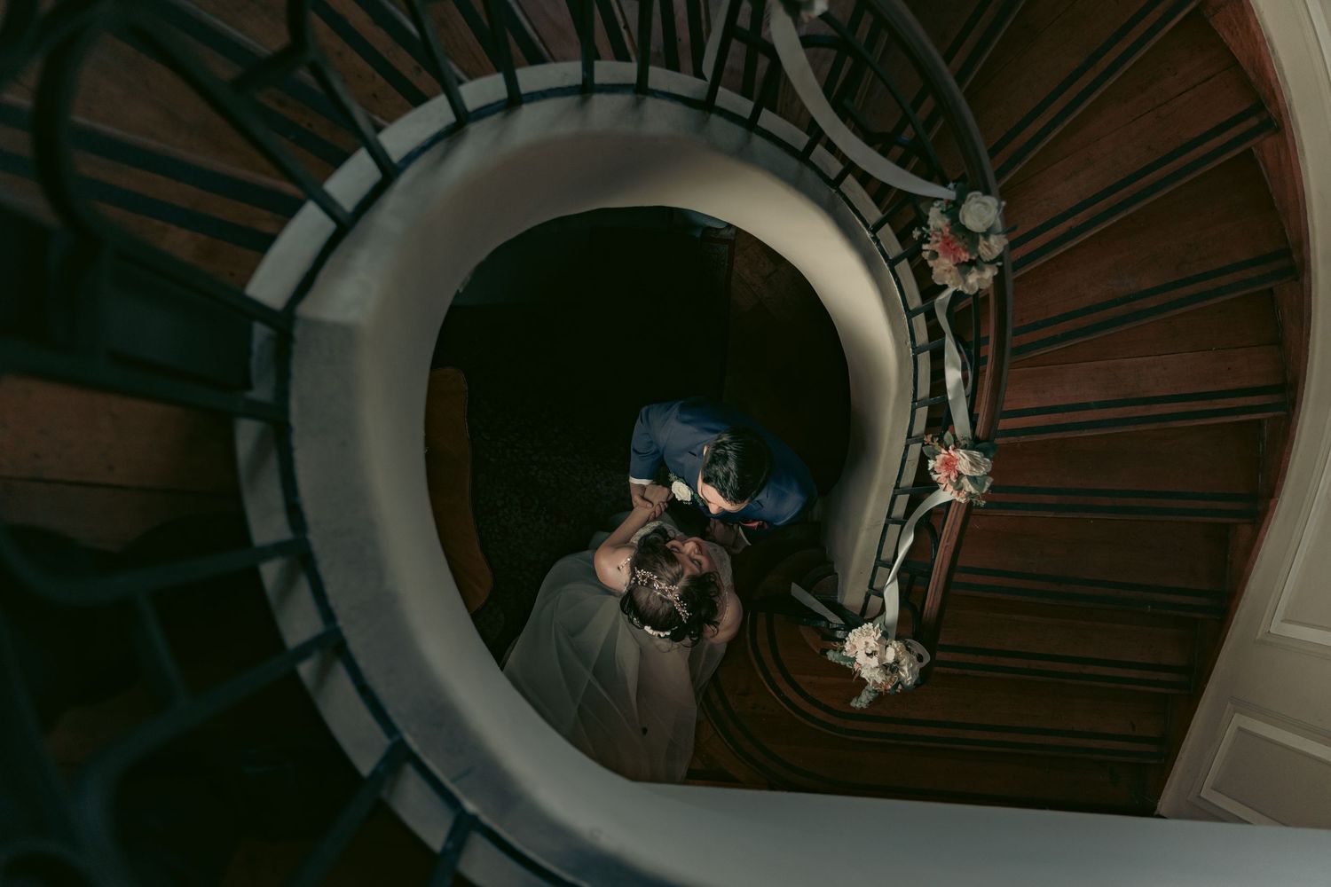 Aerial view of a spiral staircase with couple posing at different levels.
