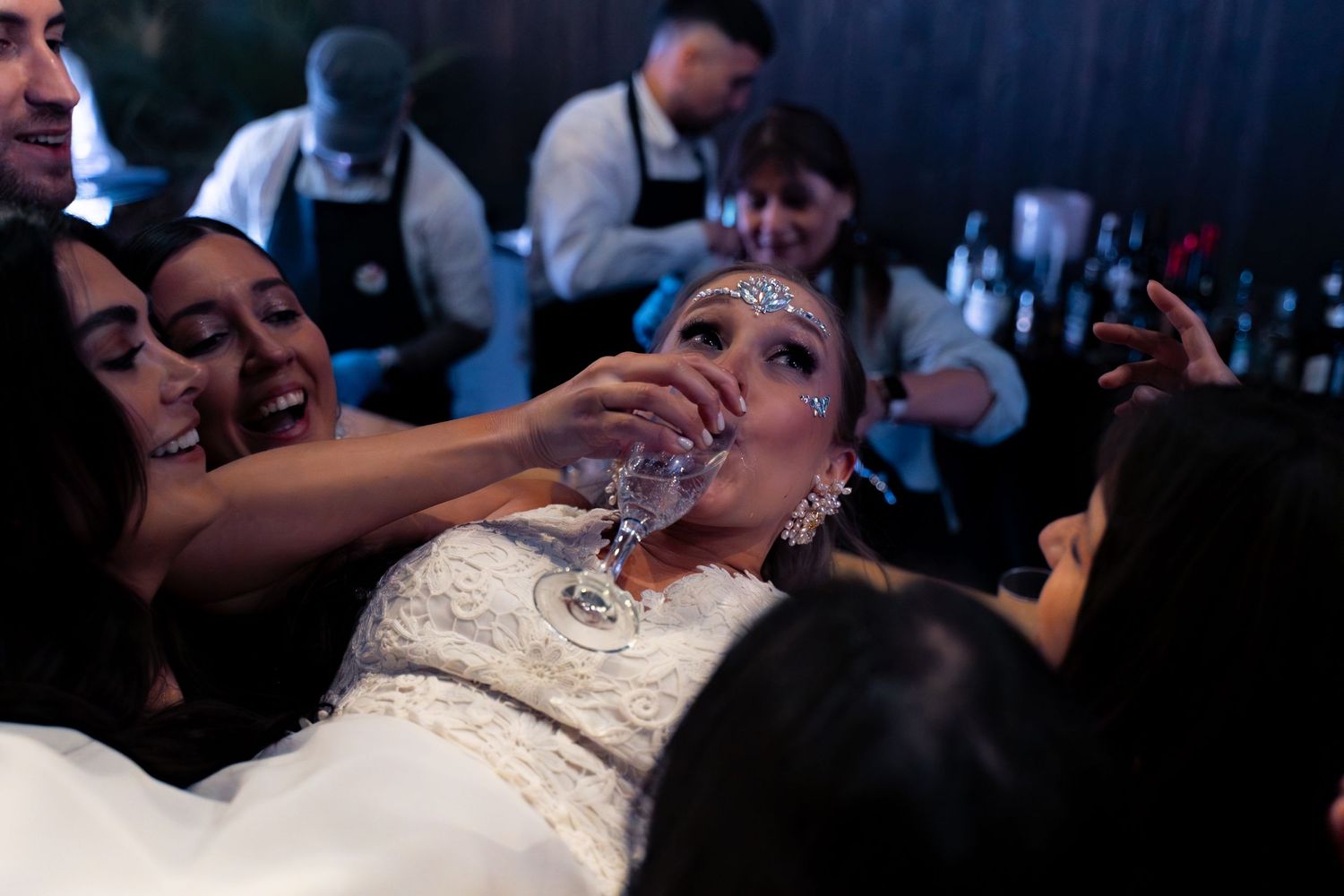Wedding celebration gets lively as guests help bride with drinks at reception.