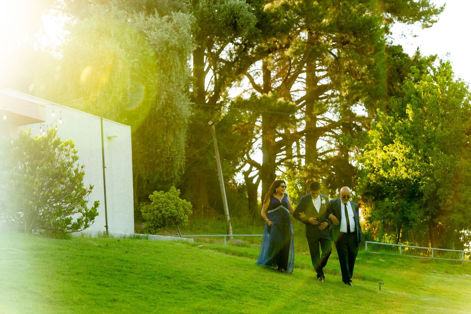 Silhouettes of people walking on grassy hillside during golden sunset.