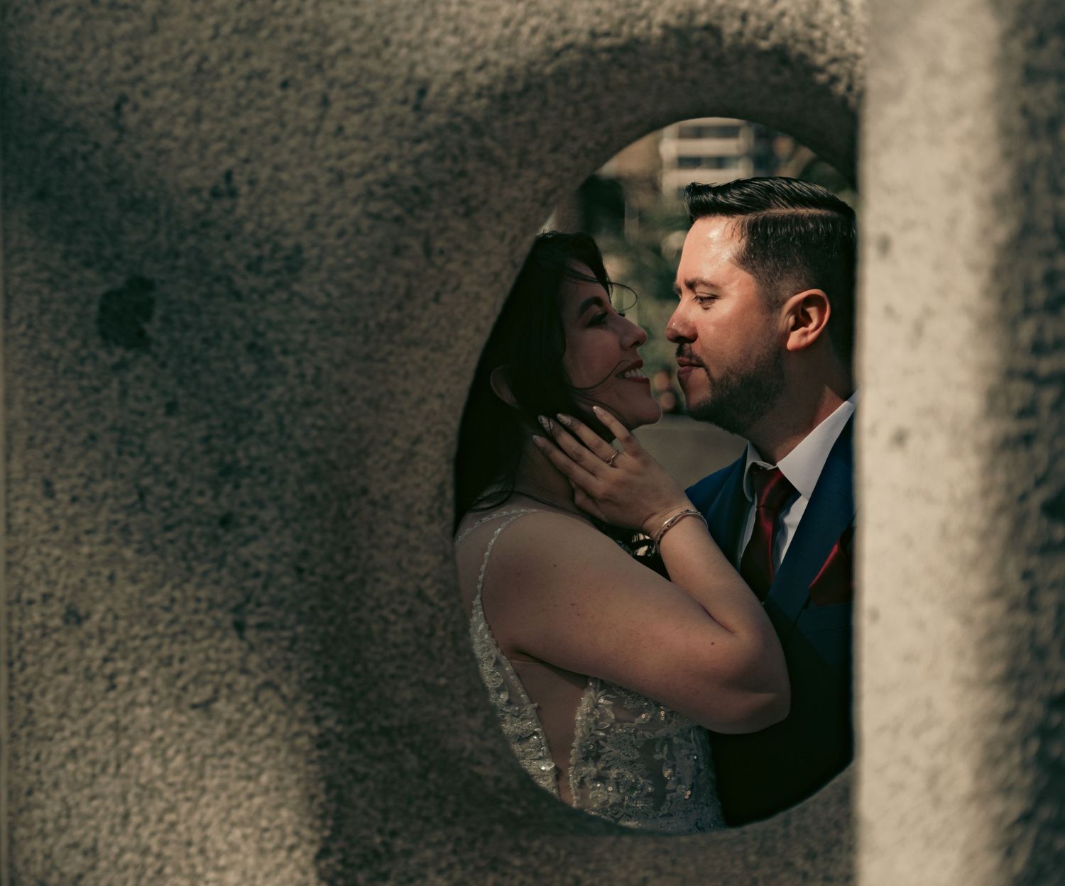 Intimate wedding couple embraces in a dimly lit corridor with dramatic shadows.