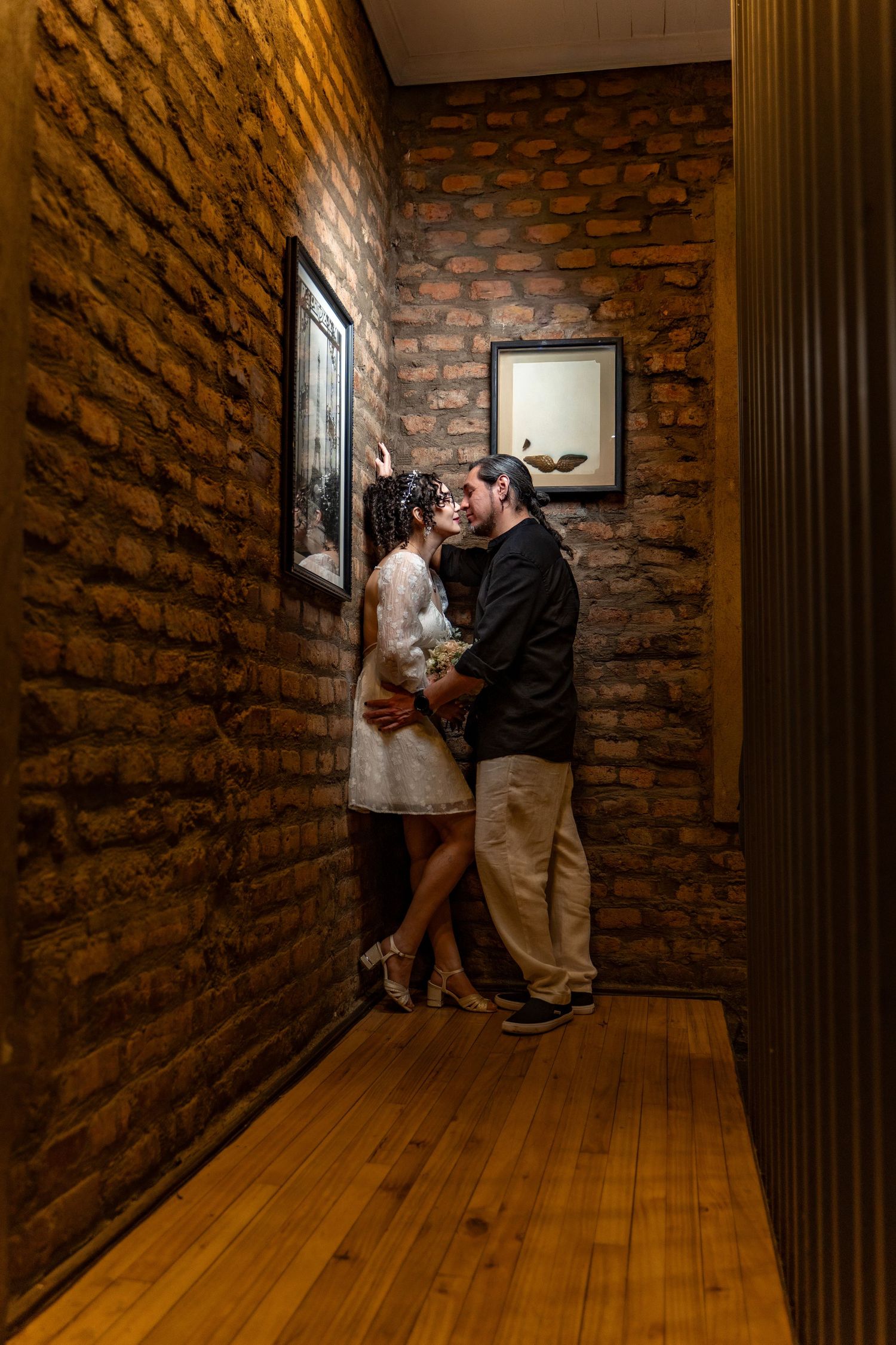 Romantic moment in a rustic brick hallway with wooden floors.