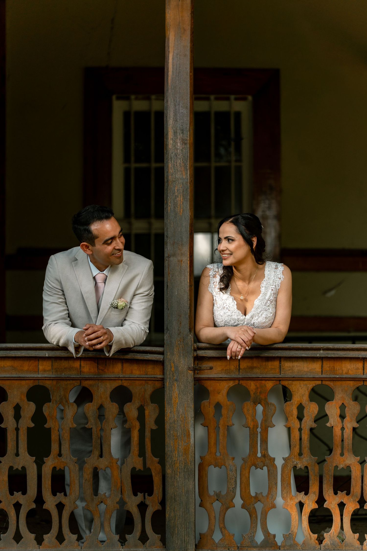 Newlyweds share tender moments on a rustic wooden balcony with vintage details.