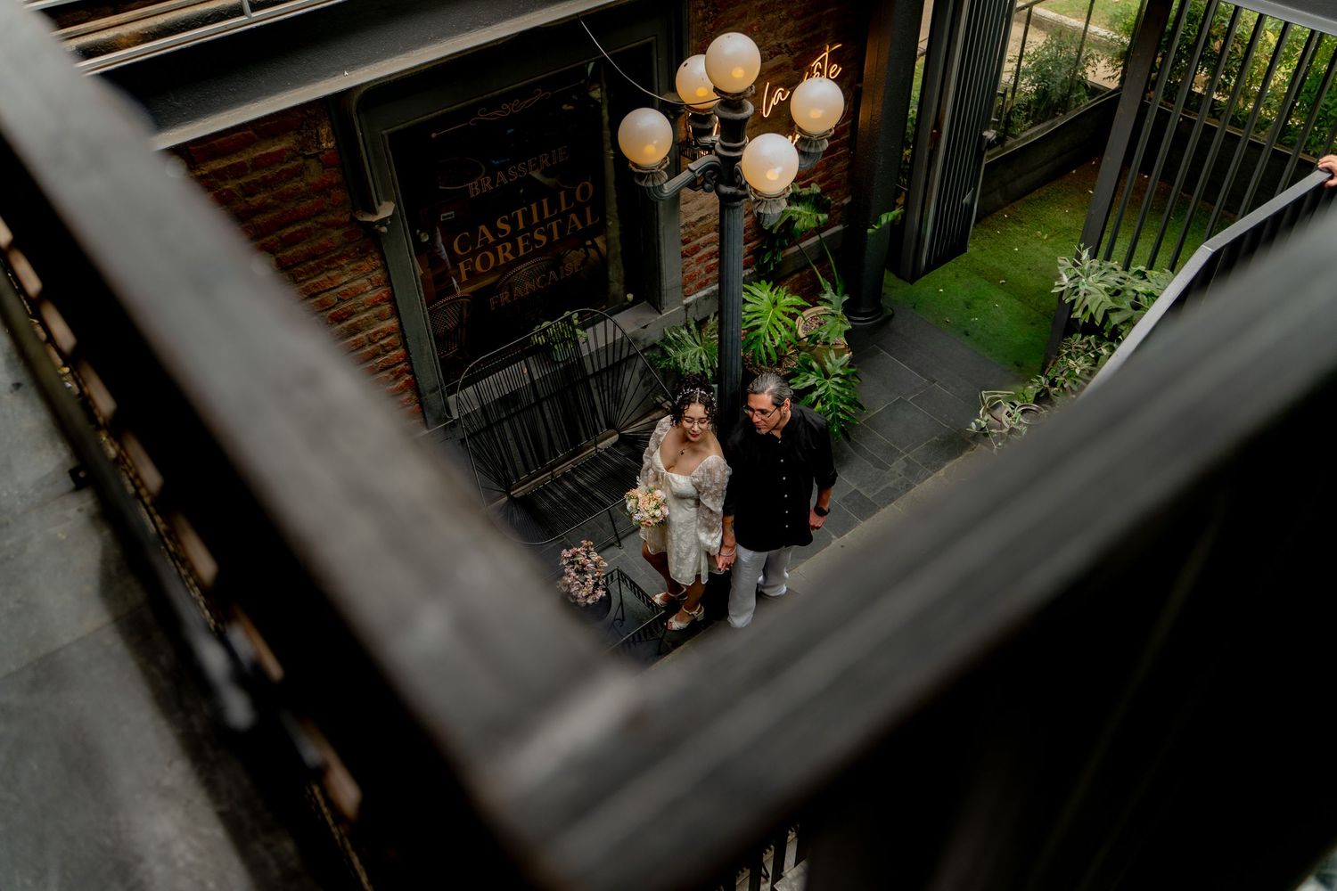 Overhead view of a couple standing beneath vintage light fixtures.