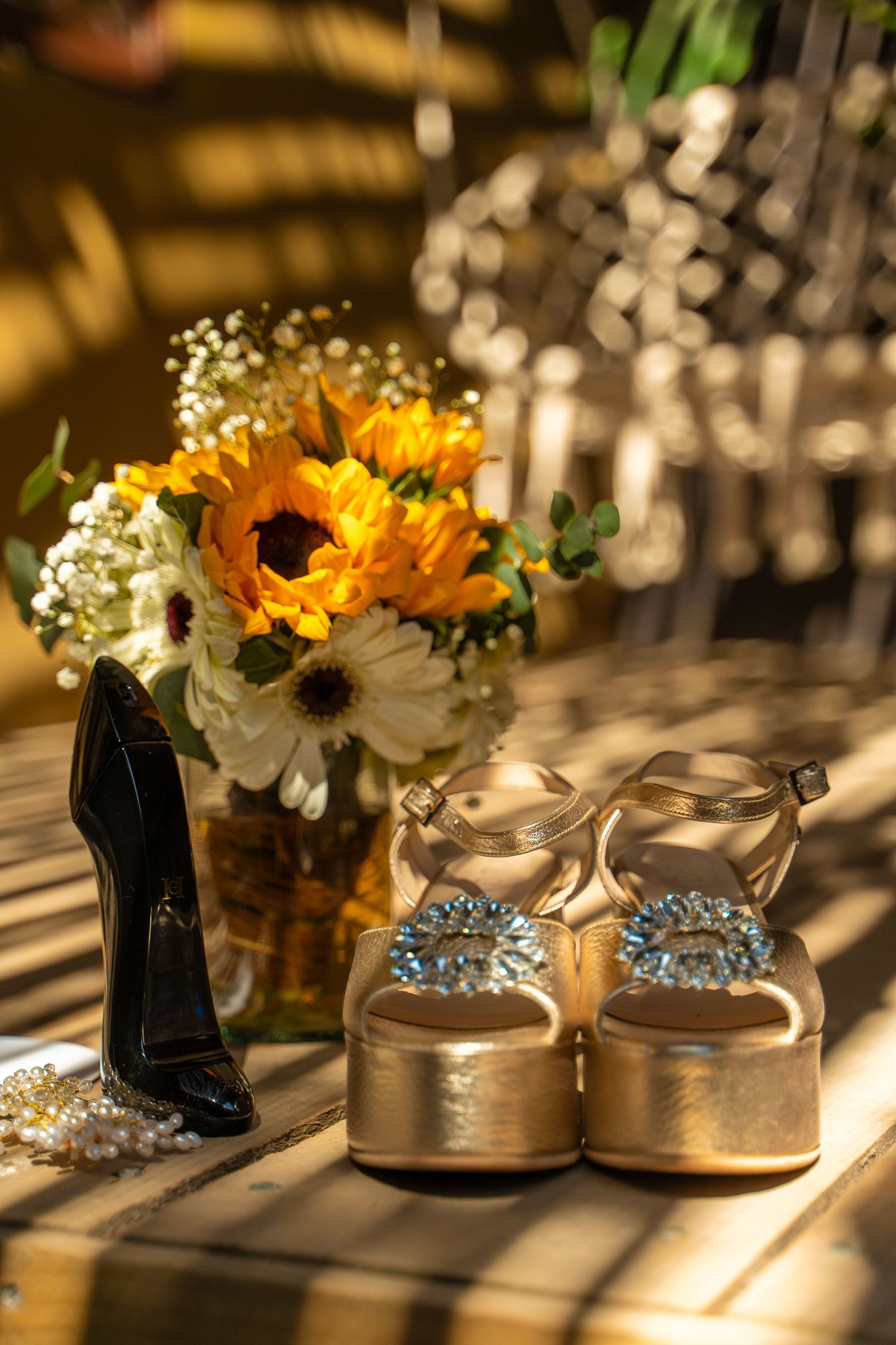 Wedding accessories with sunflowers and gold platform sandals in warm sunlight.